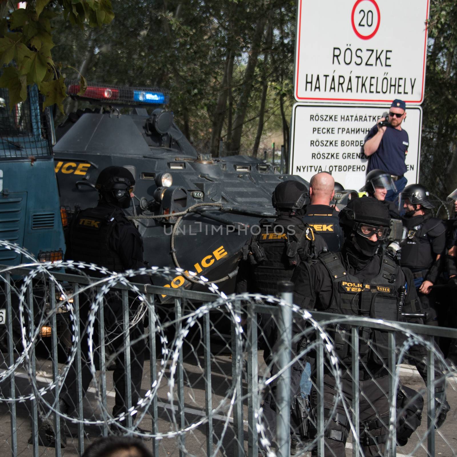 SERBIA, Horgos: Hungarian riot police wait behind barbed wire as they clashed with refugees waiting to cross the border from the Serbian border town of Horgos on September 16, 2015. 