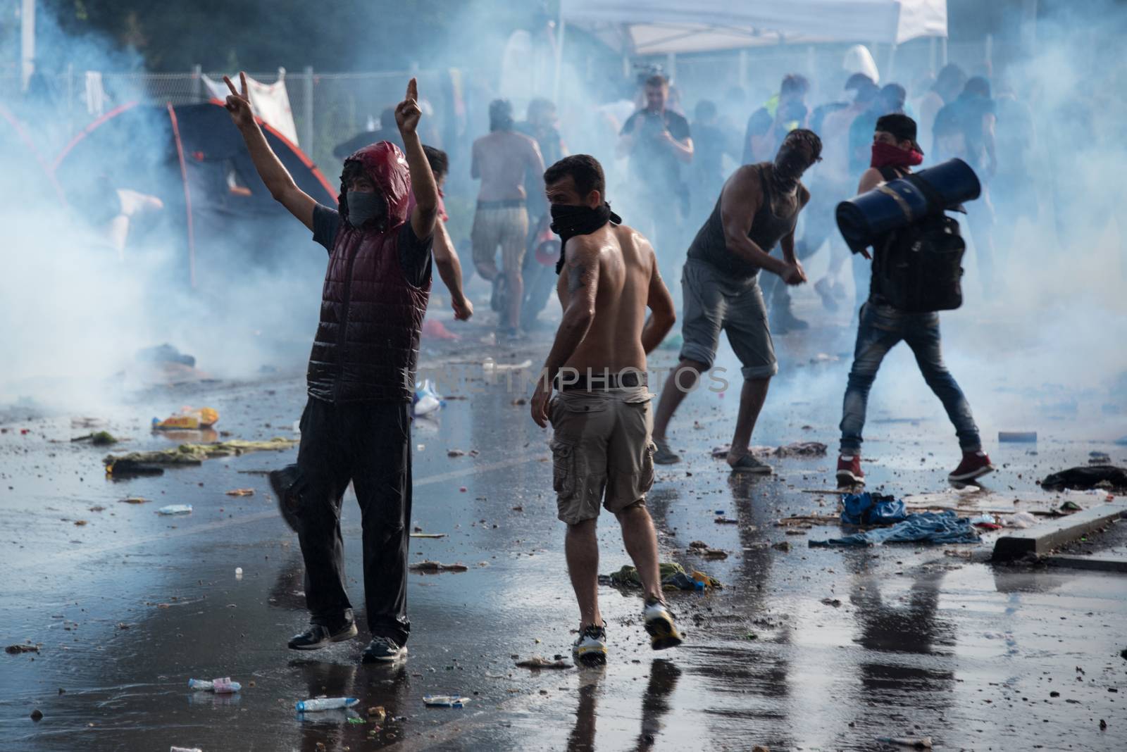 SERBIA, Horgos: Rioters stand defiant in the face of tear gas and water cannons as Hungarian riot police clash with refugees waiting to cross the border from the Serbian border town of Horgos on September 16, 2015. 