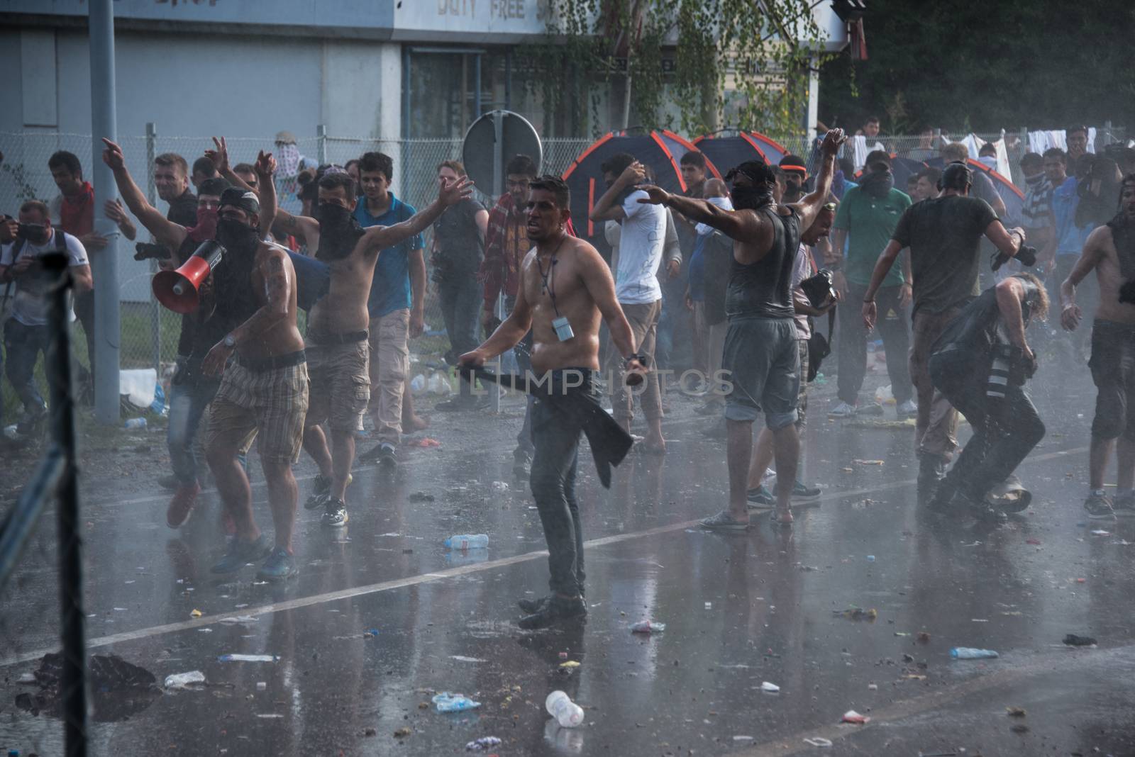 SERBIA, Horgos: Rioters stand defiant in the face of tear gas and water cannons as Hungarian riot police clash with refugees waiting to cross the border from the Serbian border town of Horgos on September 16, 2015. 