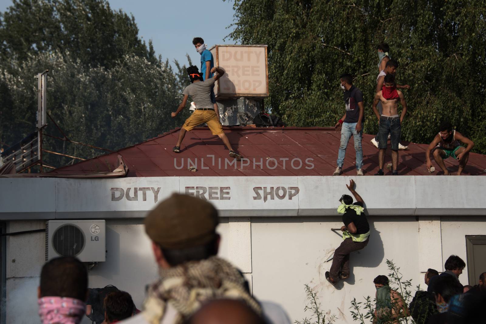 SERBIA, Horgos: Protesters jump onto a roof as Hungarian riot police clash with refugees waiting to cross the border from the Serbian border town of Horgos on September 16, 2015. 