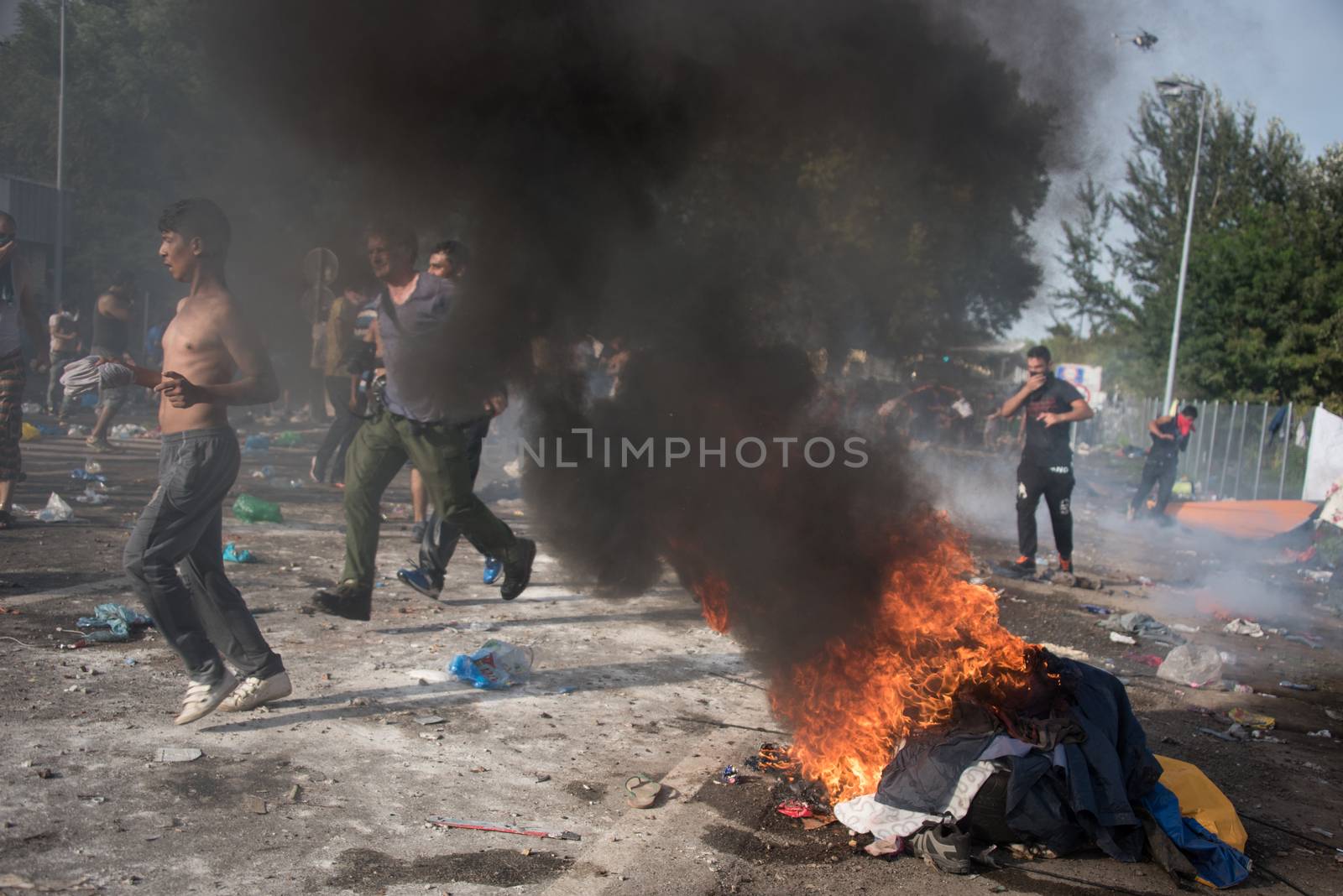 SERBIA, Horgos: Items are set on fire as Hungarian riot police clash with refugees waiting to cross the border from the Serbian border town of Horgos on September 16, 2015. 