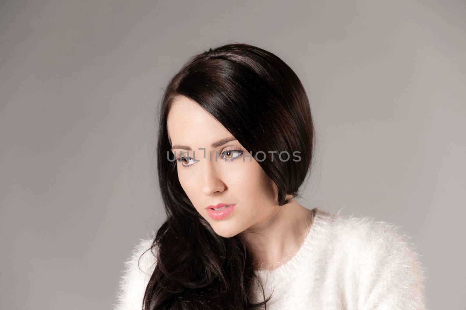 pretty woman with long dark hair on grey background