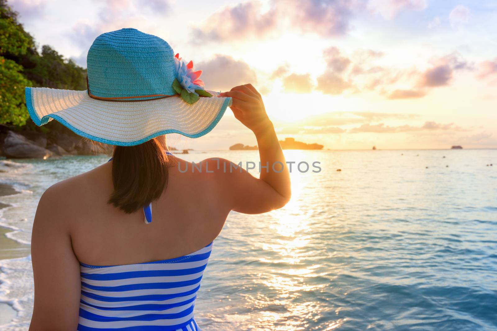 Girl with blue and white striped swimsuit standing watch nature sky and sea during the sunrise on beach of Honeymoon Bay at Koh Miang, Similan Islands National Park, Phang Nga, Thailand