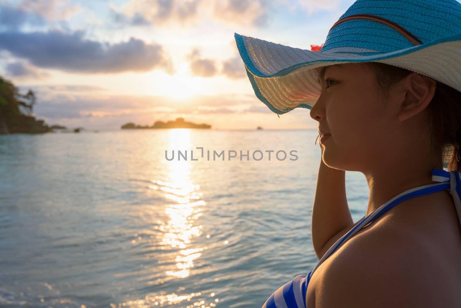 Girl with blue and white striped swimsuit standing watch nature sky and sea during the sunrise on beach of Honeymoon Bay at Koh Miang, Similan Islands National Park, Phang Nga, Thailand