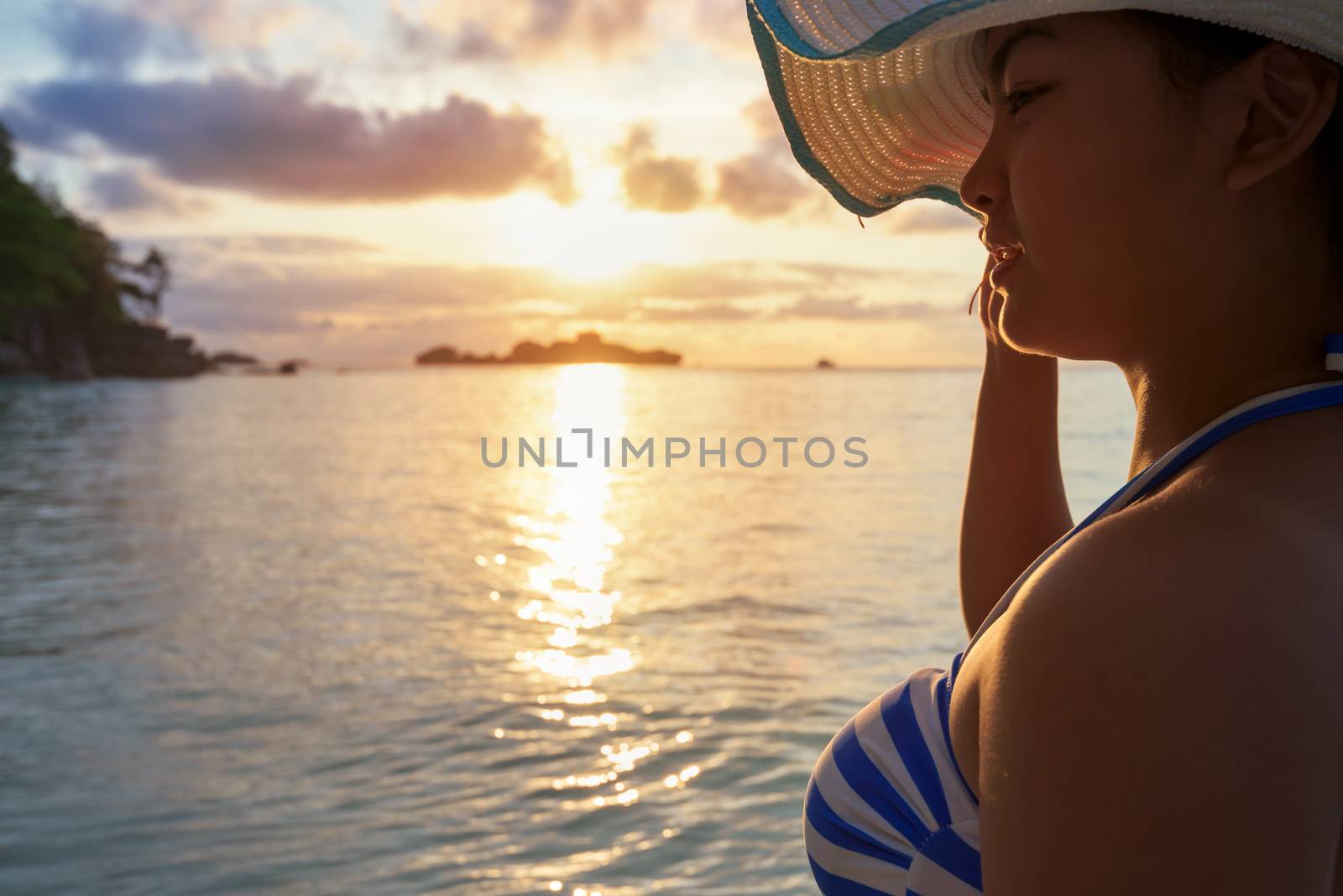 Girl with blue and white striped swimsuit standing watch nature sky and sea during the sunrise on beach of Honeymoon Bay at Koh Miang, Similan Islands National Park, Phang Nga, Thailand