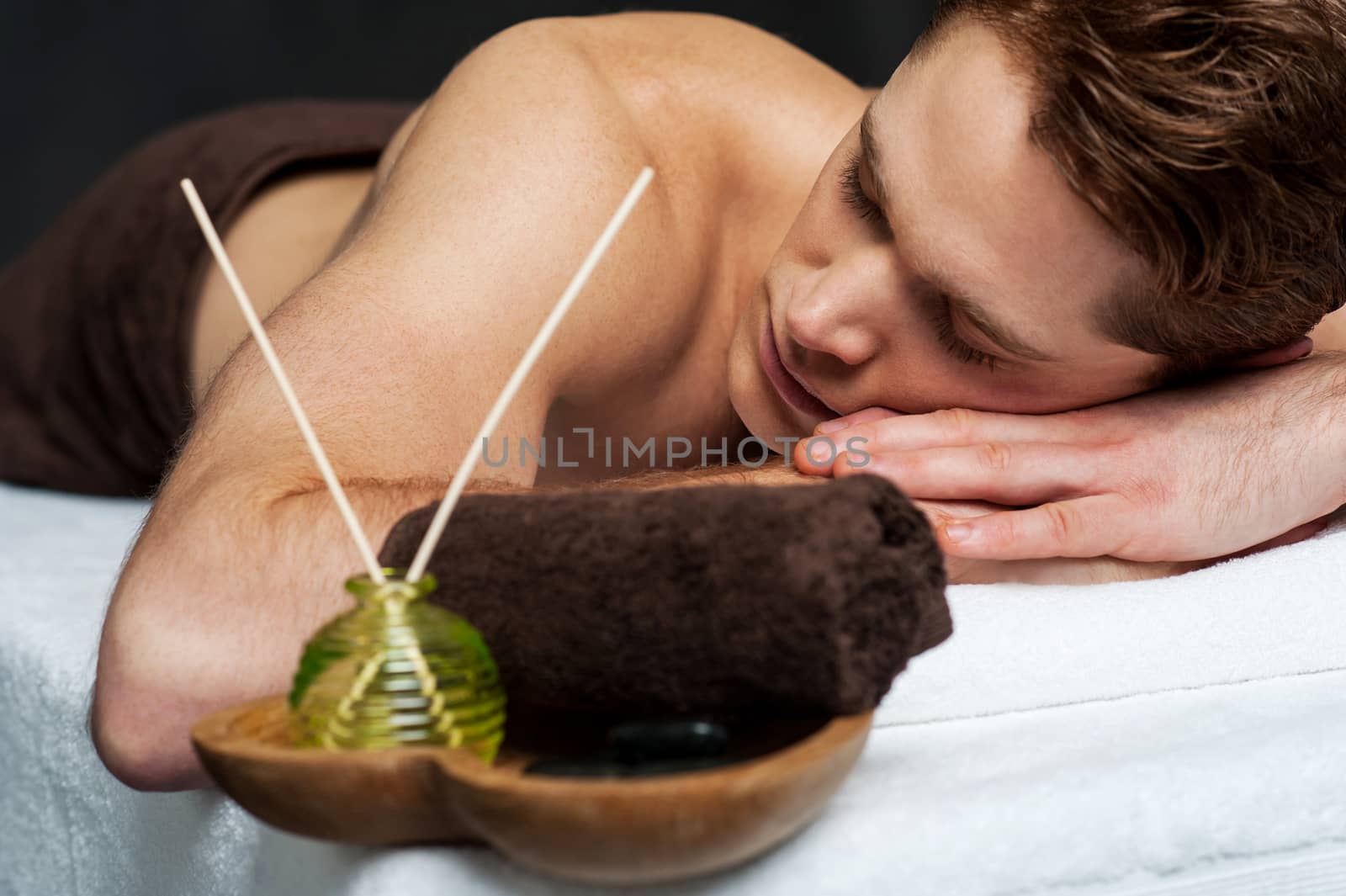 Young male is lying and relaxing in spa salon