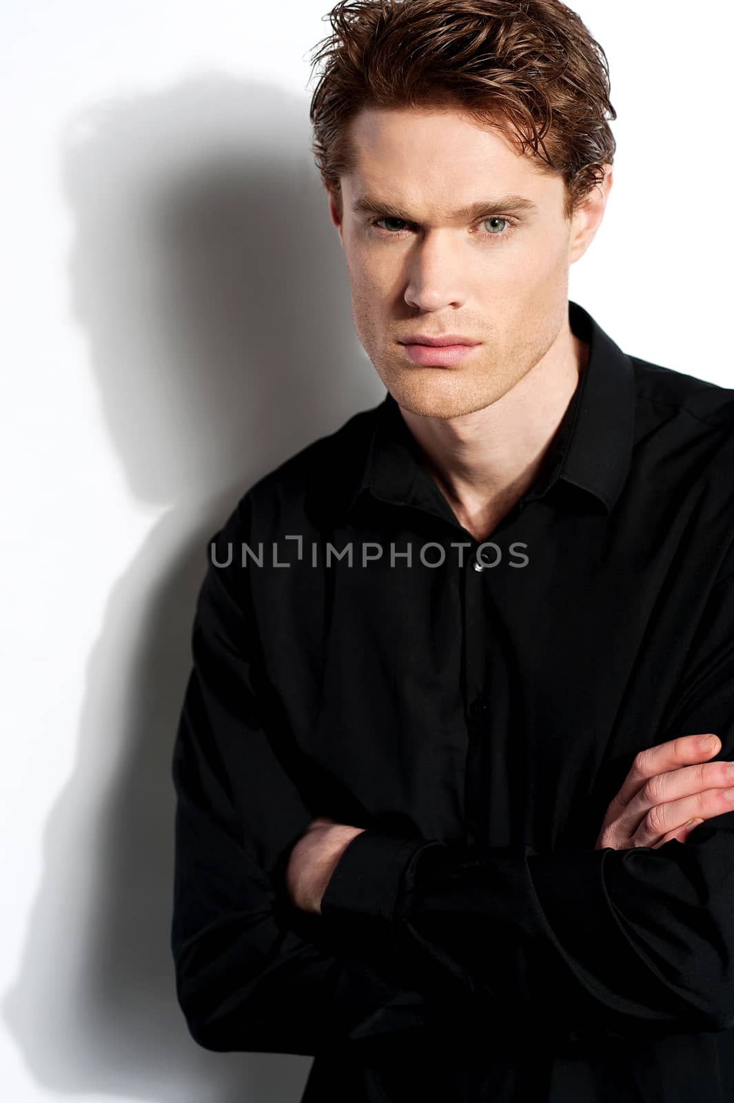 Young stylish male posing with folded arms