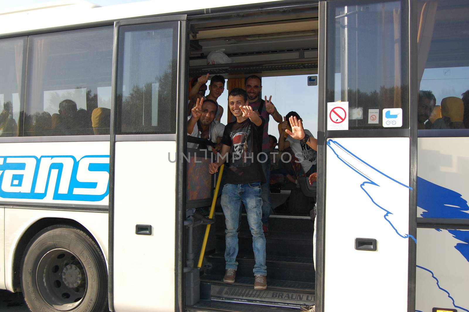 SERBIA, Border with Croatia: Refugees aboard a bus wave as hundreds are  stranded at the Serbian-Croatian border on September 18, 2015 after Croatia decided to shut their border with Serbia.This decision was made after more than 11,000 refugees entered Croatia in a single day. Refugees had to spend entire night and half of the next day at the border. Local authorities in Serbia have organized bus transportation to take the refugees from the border to the reception camps.