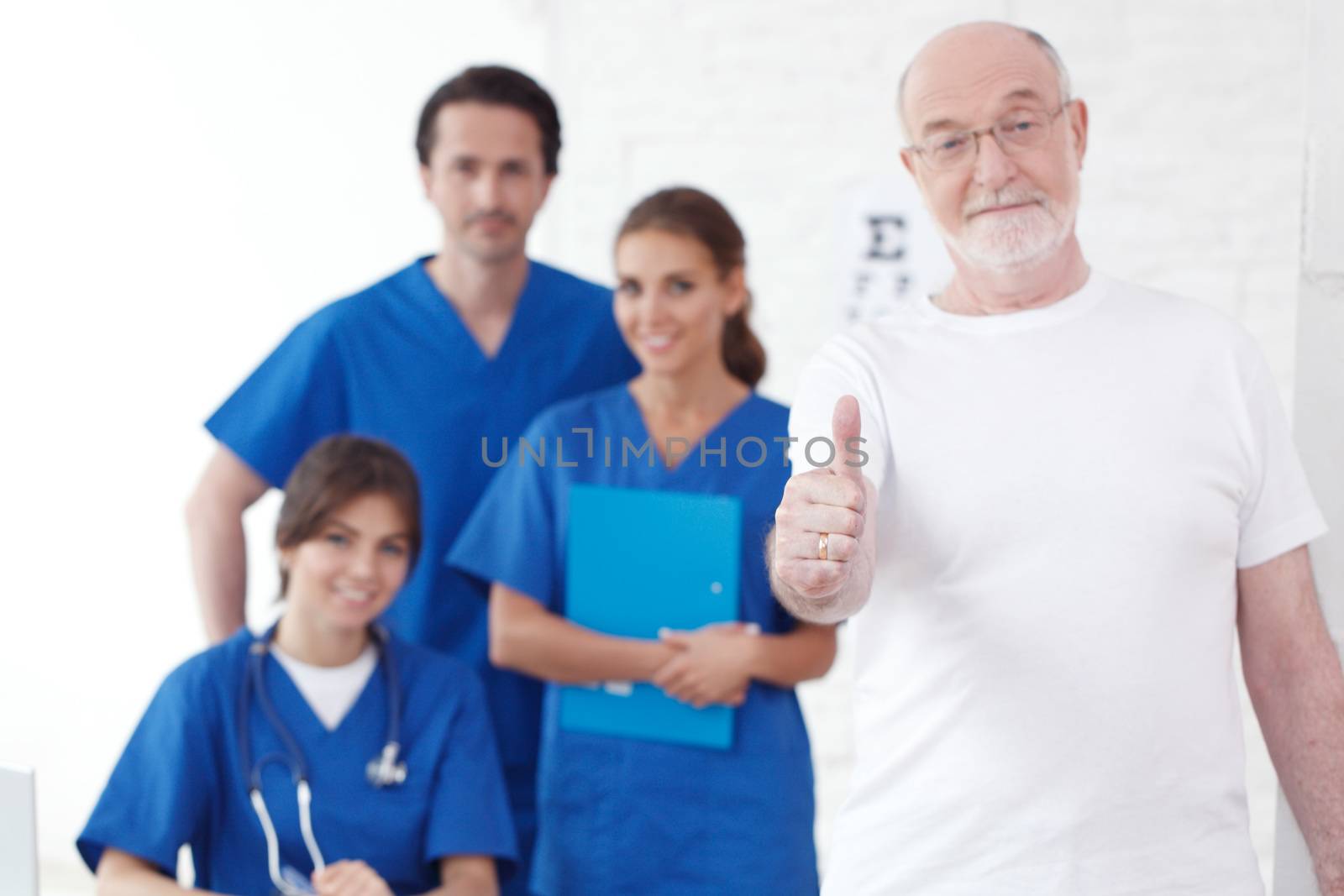 Happy senior patient with thumbs up and his doctors