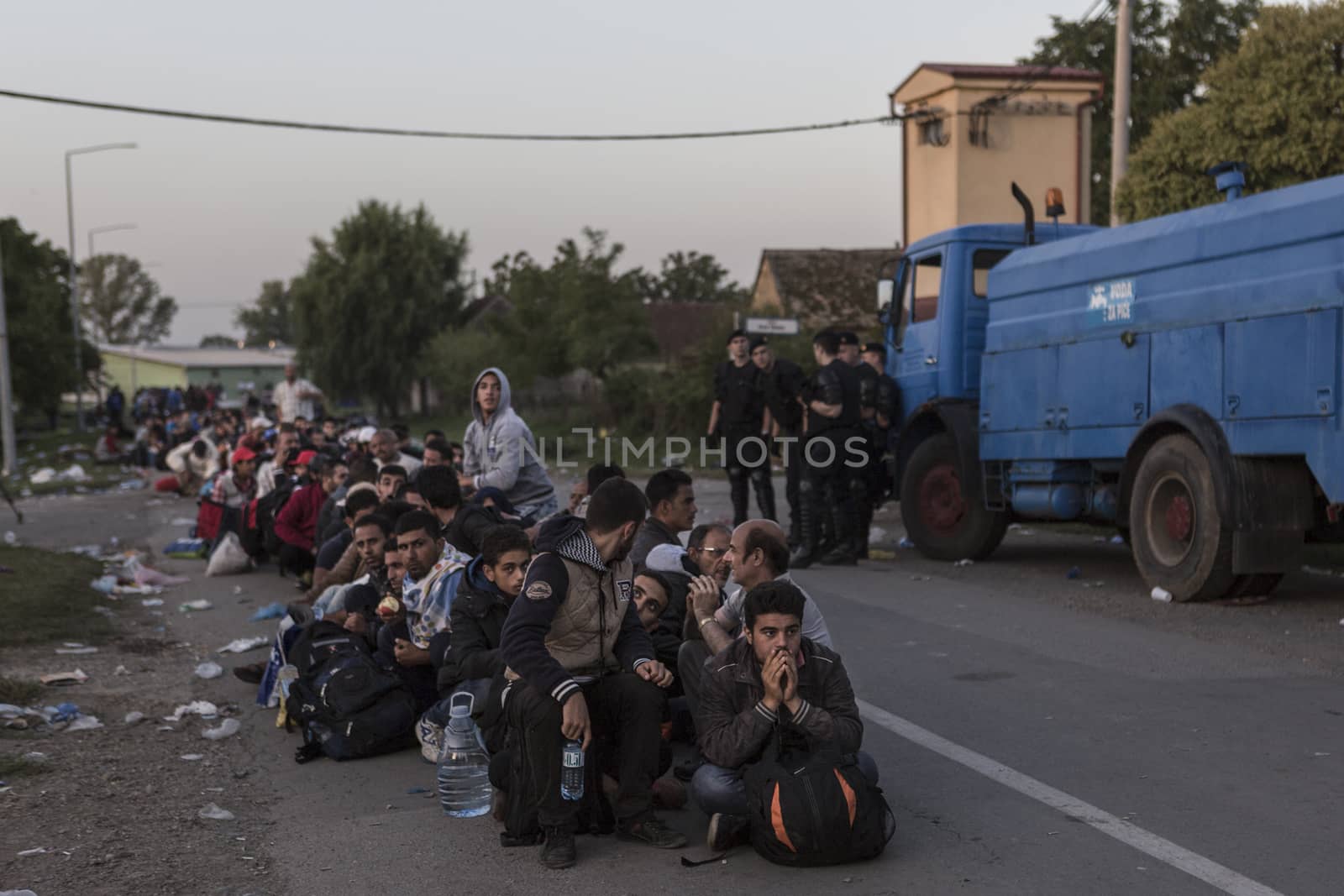 CROATIA, Tovarnik: Refugees wait in line in Tovarnik, Croatia near the Serbian-border while police watch on in the background on September 18, 2015. Refugees are hoping to continue their journey to Germany and Northern Europe via Slovenia 