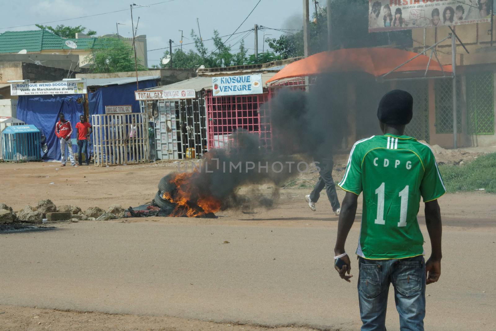 BURKINA FASO, Ouagadougou : A man stands in front of a burning tire near the presidential palace in Ouagadougou, Burkina Faso, on September 18, 2015. Protests have sparked in Ouagadougou after Presidential guard officers seized power in a coup.