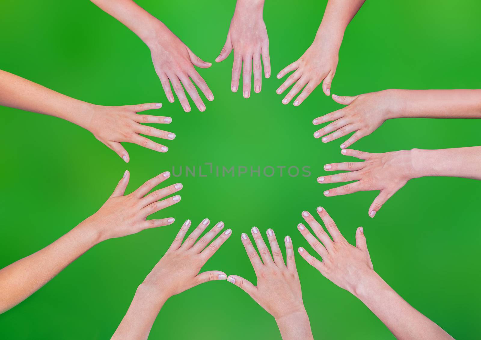 Five children hands joining in circle above green background by BenSchonewille