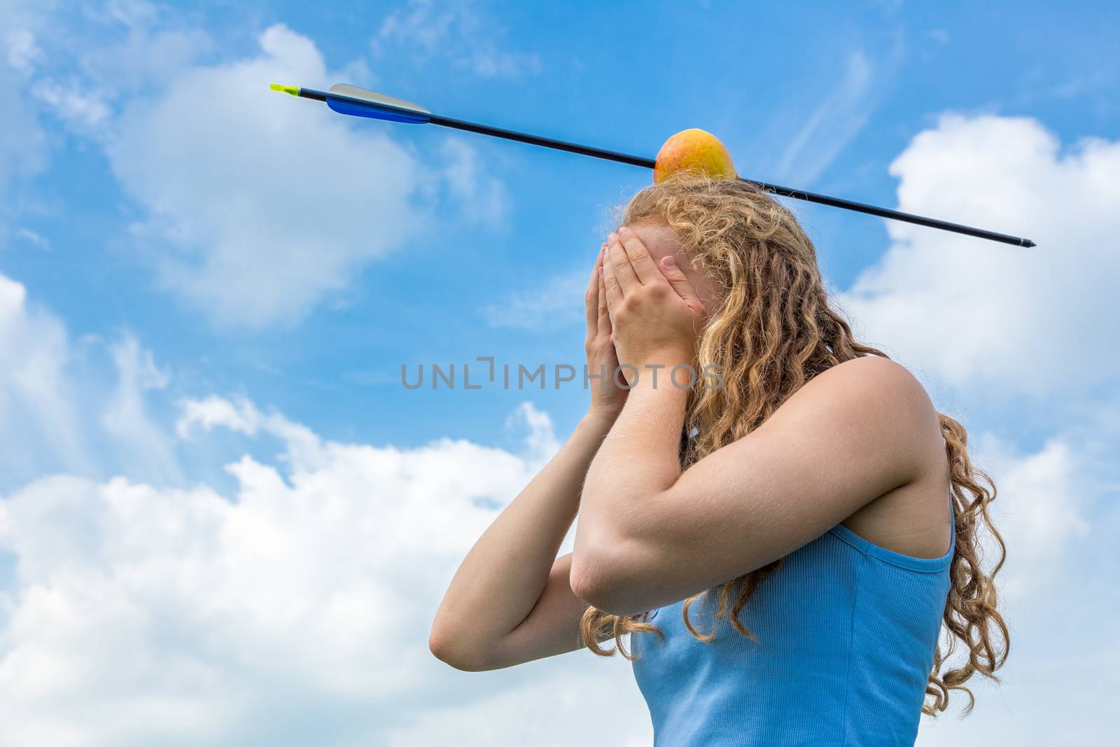 Teenage girl covering her face feeling fear with apple and arrow on head