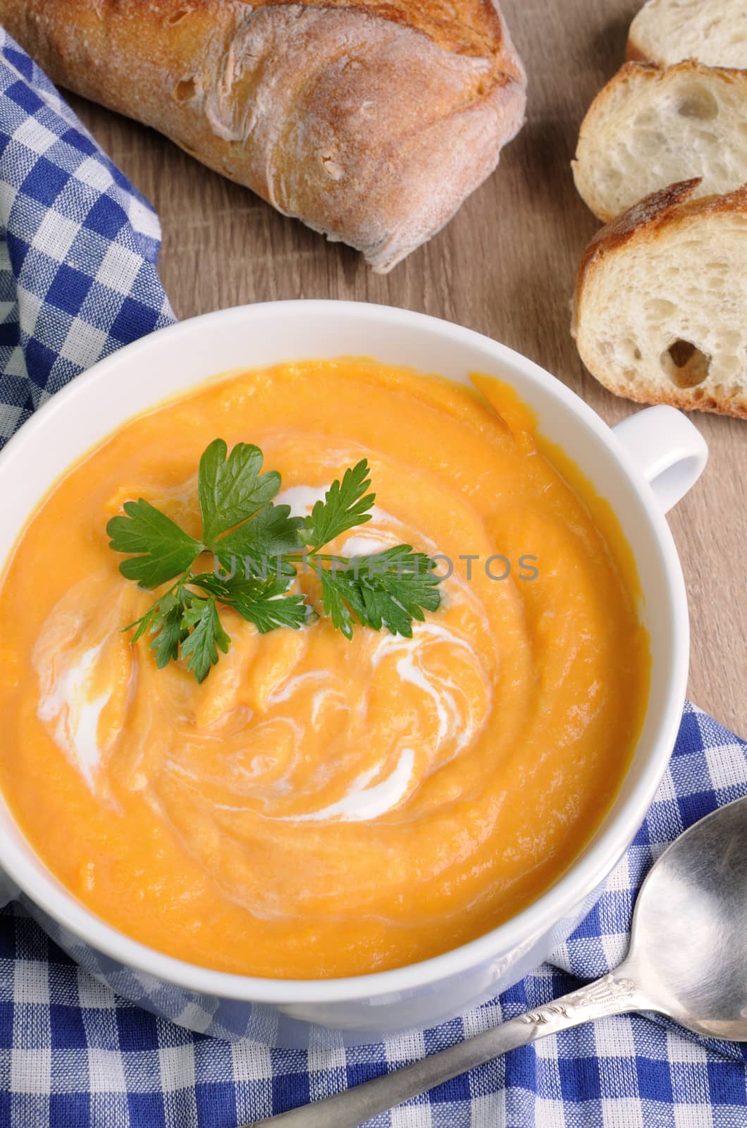 Pumpkin puree soup with  parsley  a plate on the table with bread