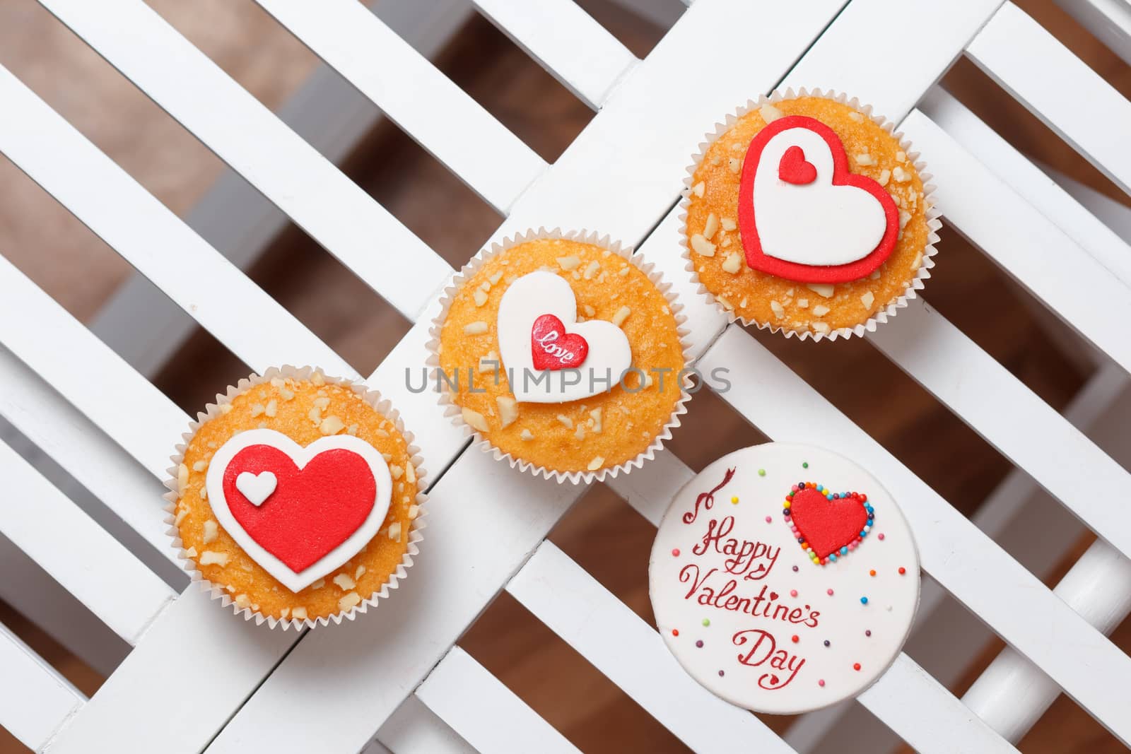 valentine's day muffins with red and white hearts on a white wooden table with a note