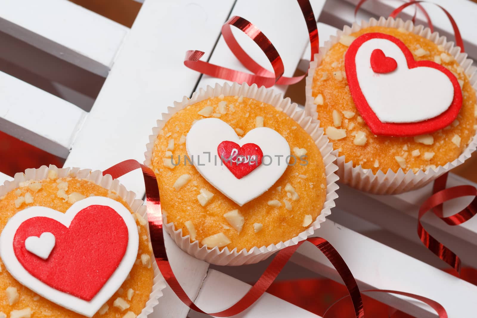 valentine's day muffins with red and white hearts on a white wooden table with a note and ribbon