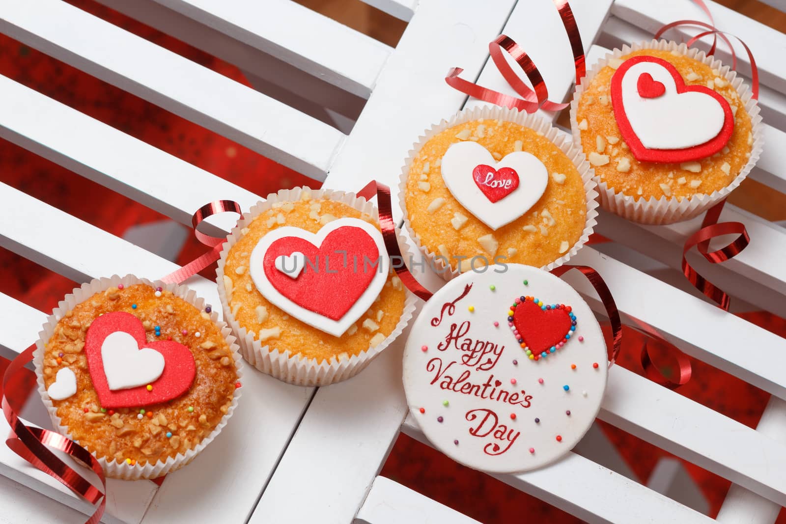 valentine's day muffins with red and white hearts on a white wooden table with a note and ribbon