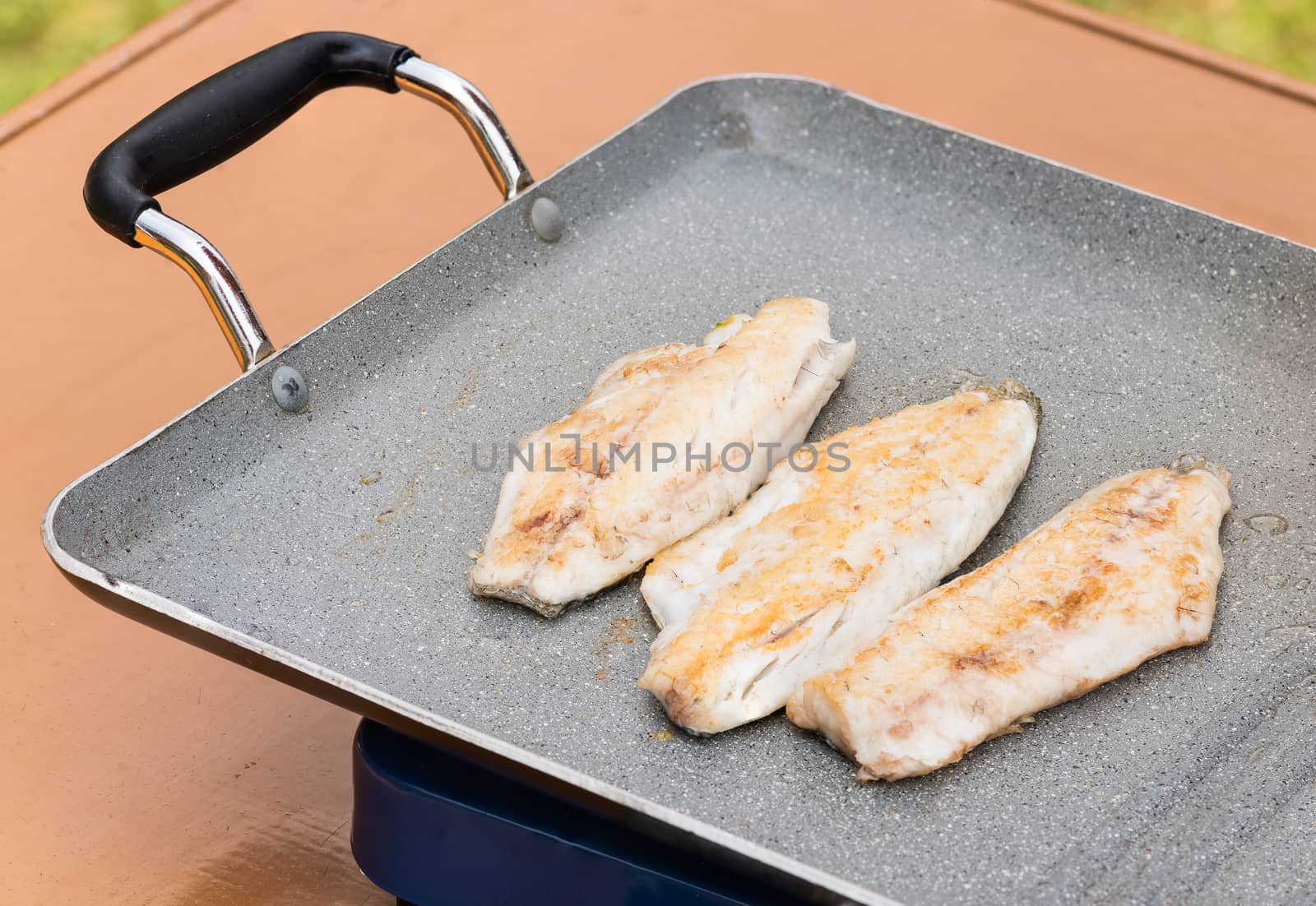 Pictured three fillets of sea bream cooked on the grill outdoor.