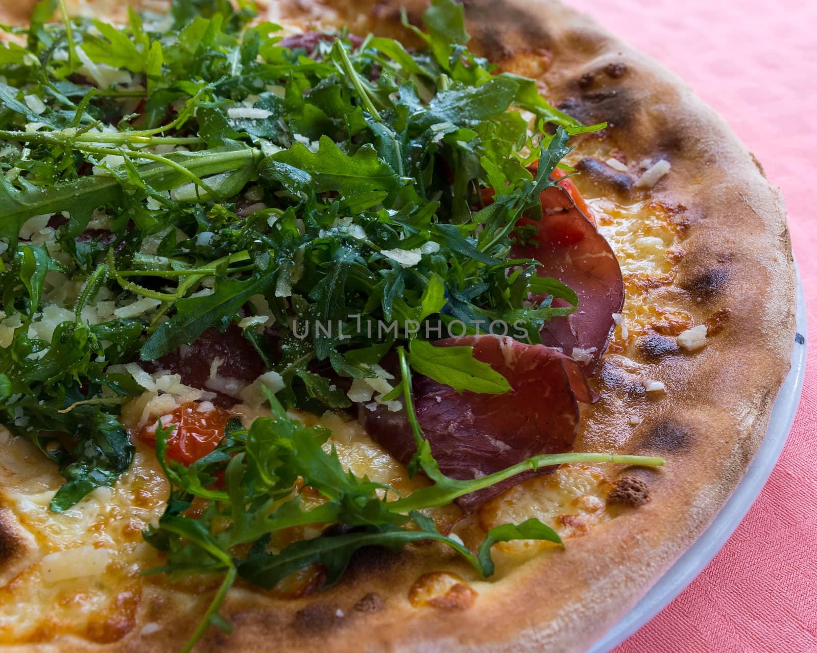 In the picture Italian pizza  with Arcula,cherry tomato,tomato,cheese,mozzarella,parmesan and Bresaola.