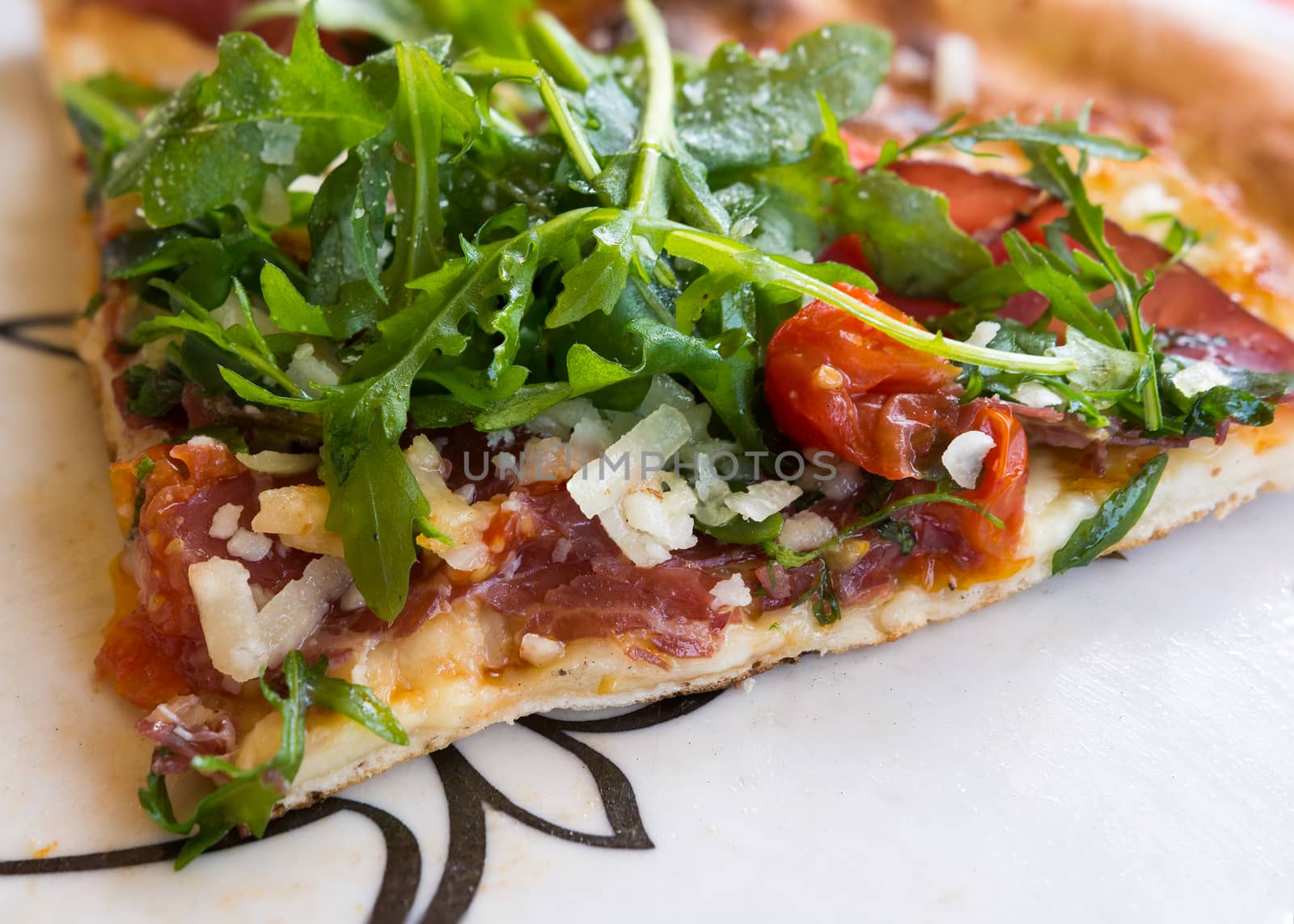 In the picture Italian pizza close-up with Arcula,cherry tomato,tomato,mozzarella,cheese,parmesan and Bresaola.