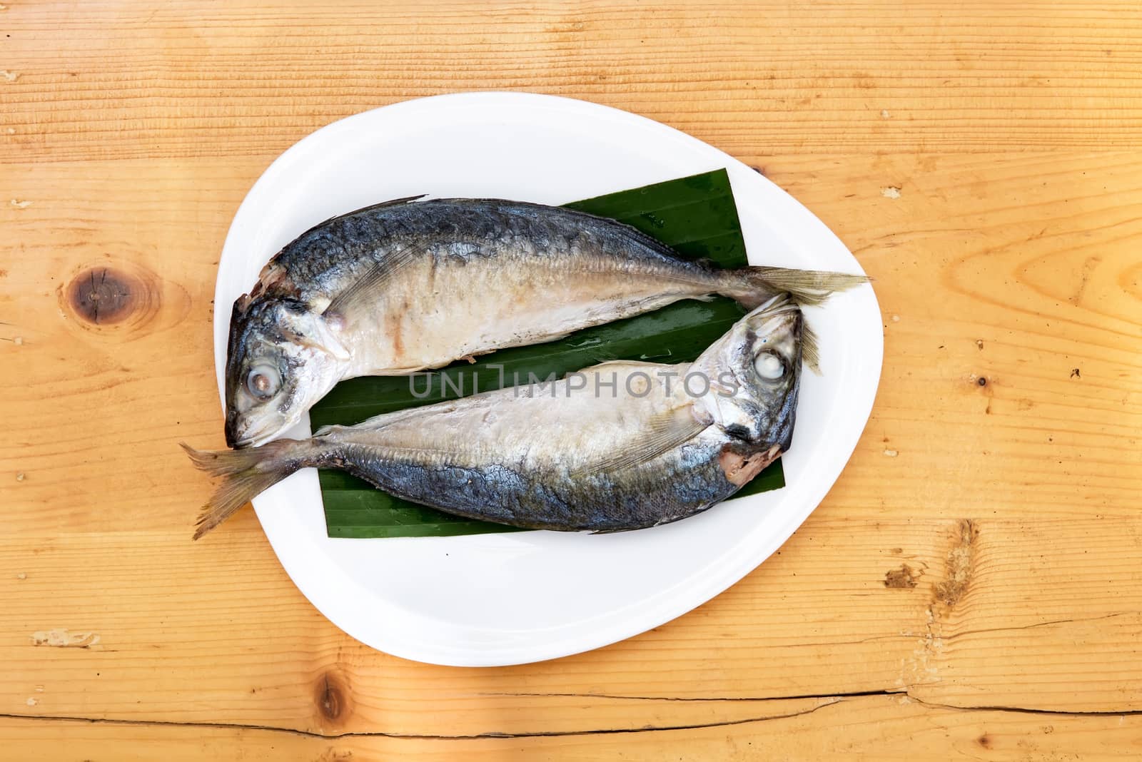 steam with mackerel in white dish on wood table .