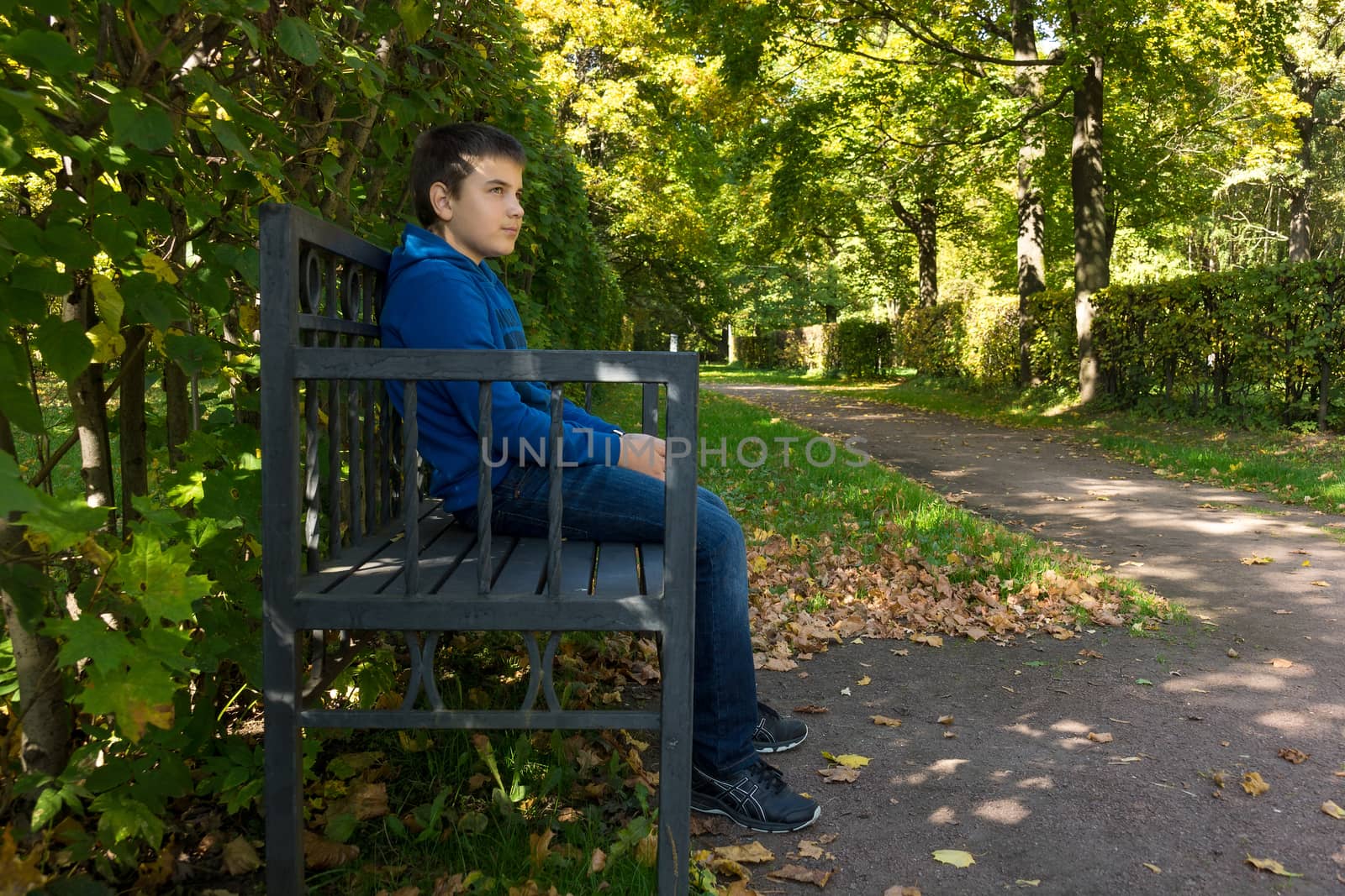 The photo depicts a boy sitting on a bench