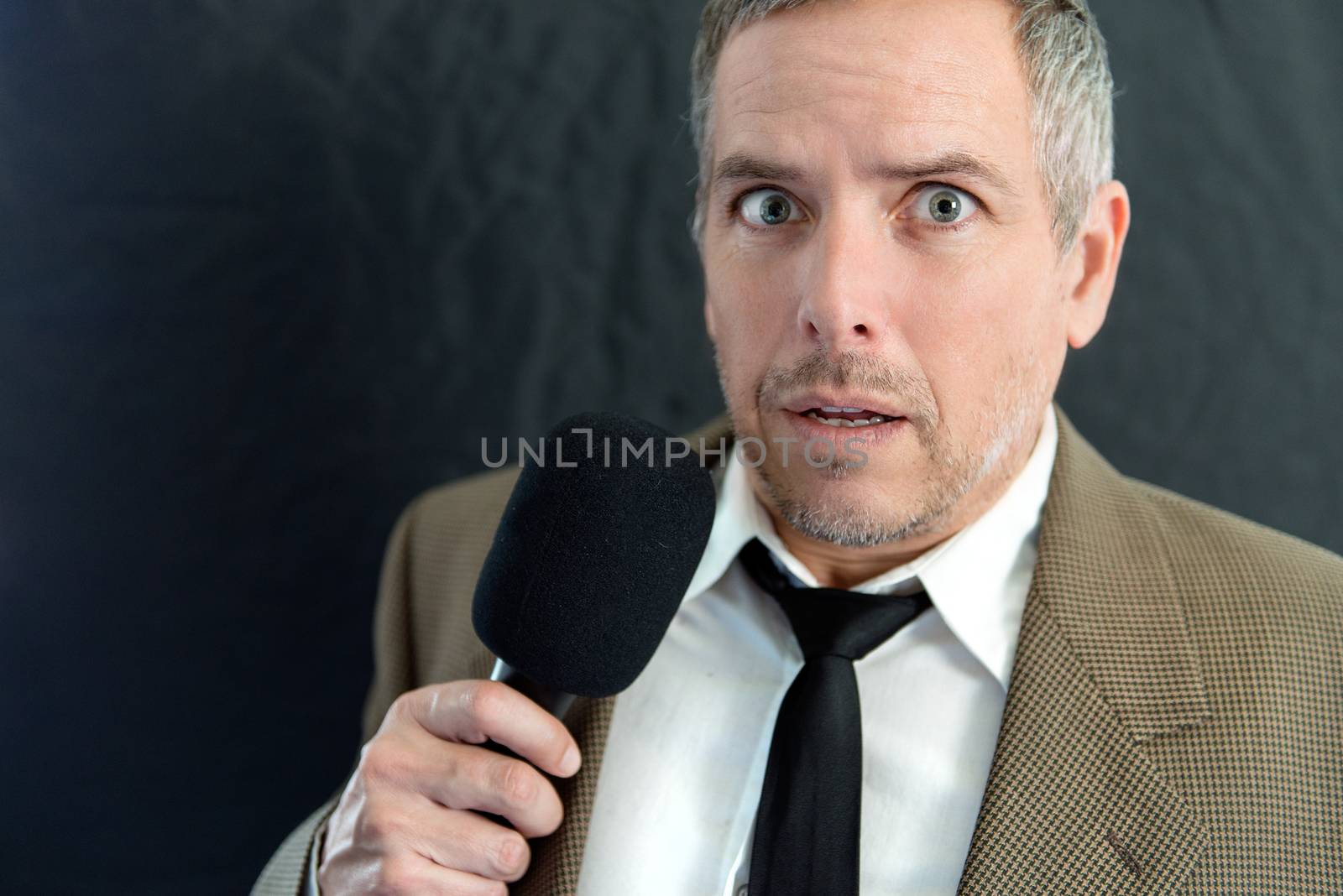Close-up of an anxious man speaking into microphone.