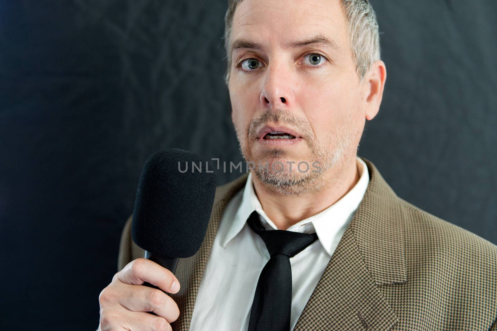 Close-up of a depressed man speaking into microphone.