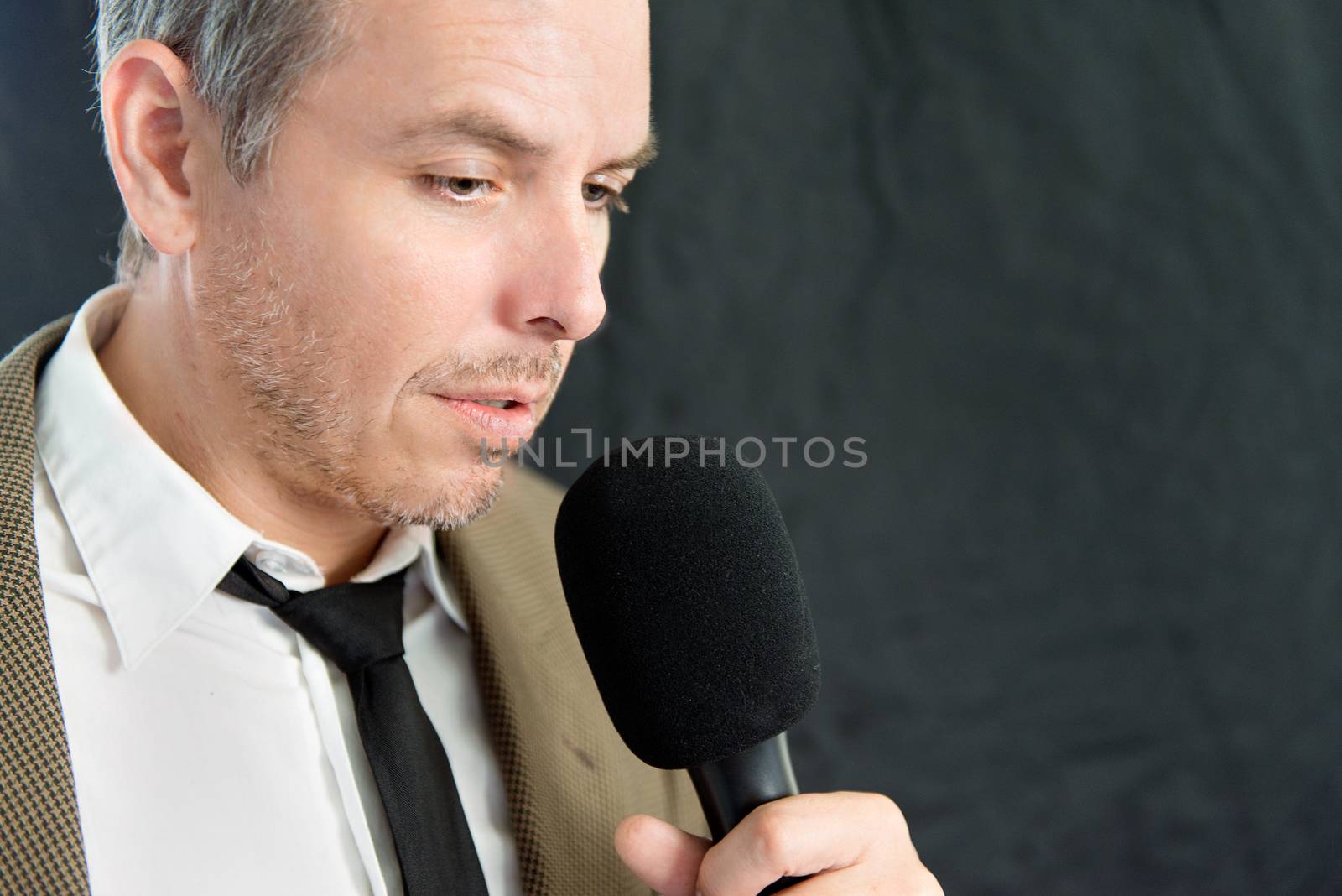 Close-up of serious man speaking into microphone, side.