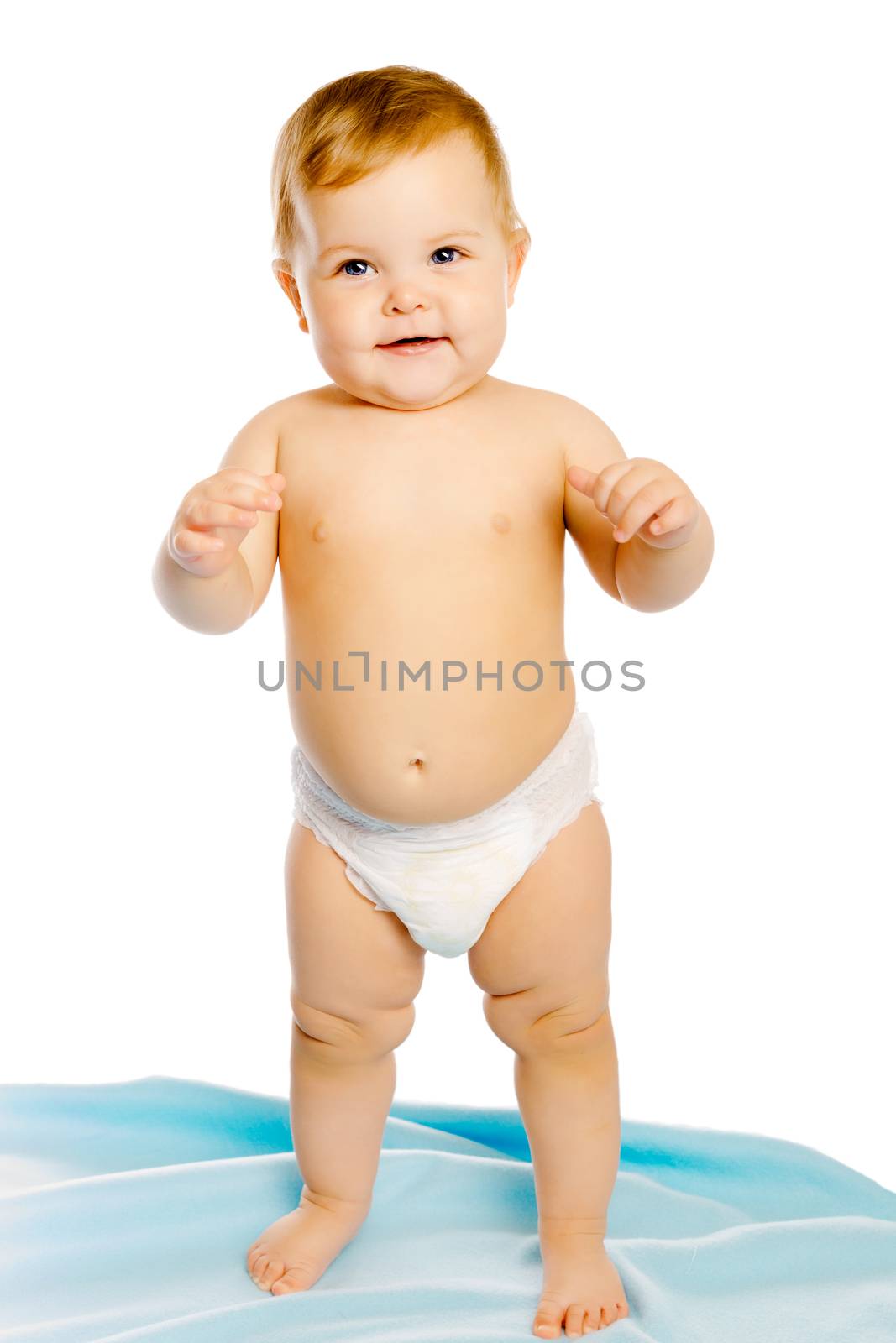 Funny baby in diaper standing on a blue blanket. Studio. Isolated