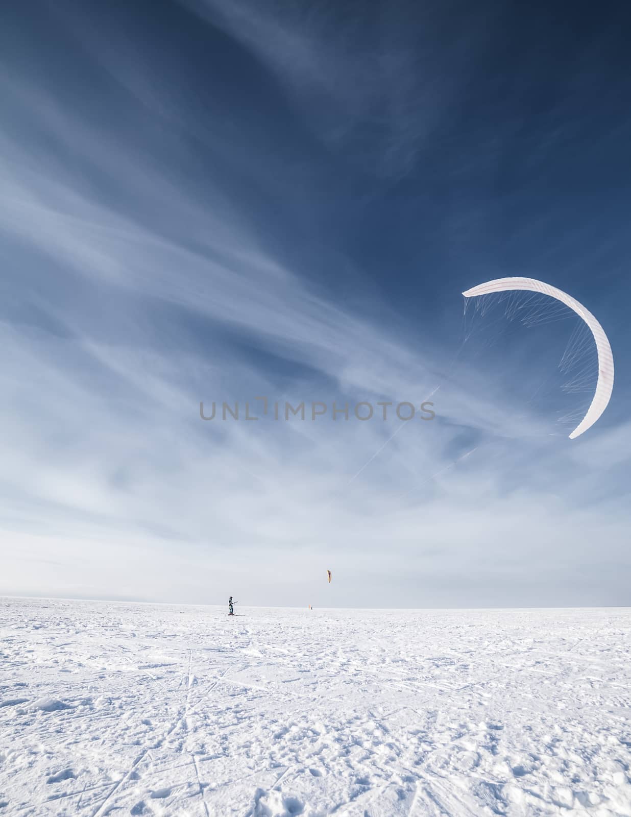 Kite surfer being pulled by his kite across the snow