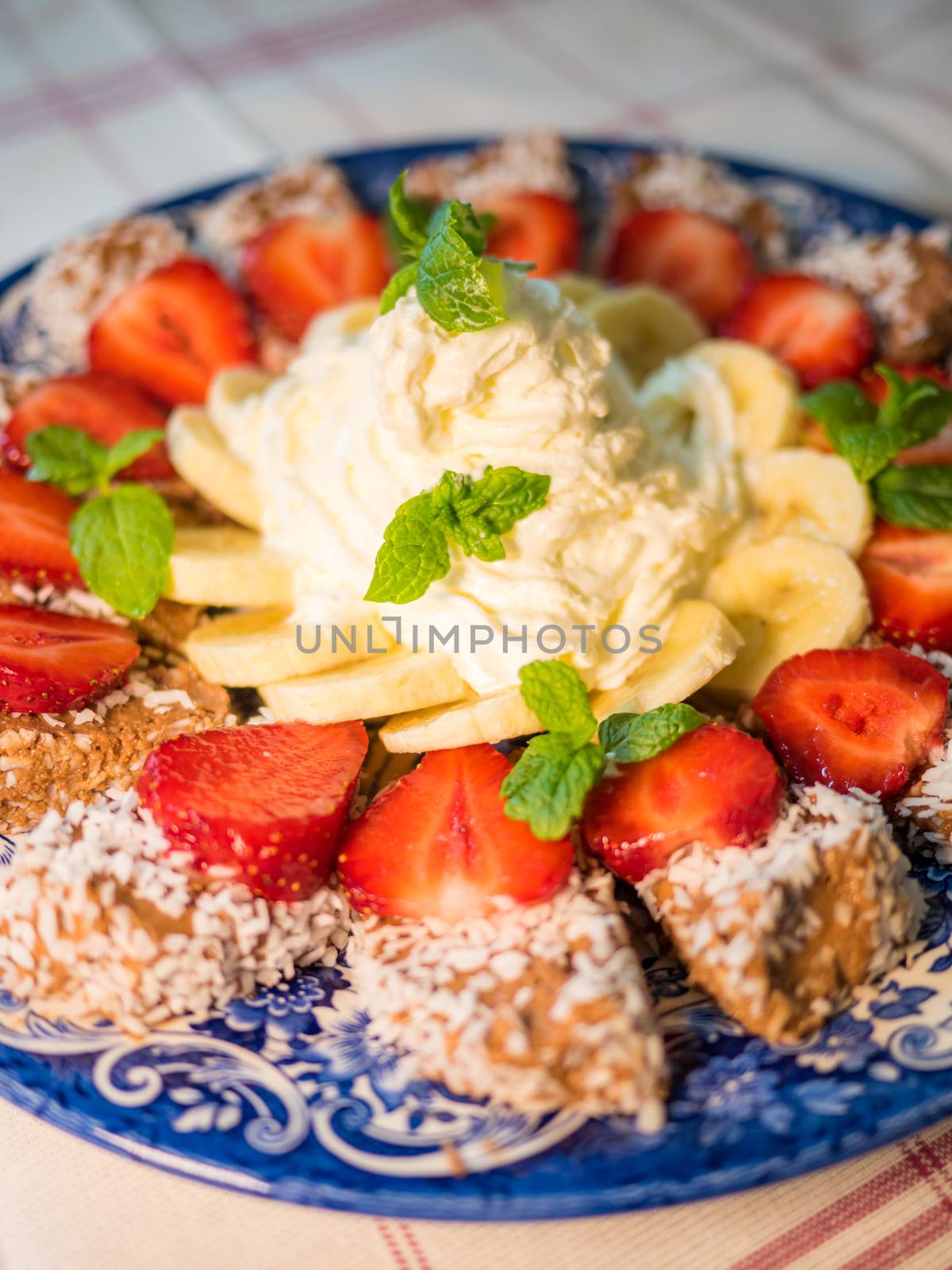 Chocolate dessert with banana, strawberry and mint under whipped cream