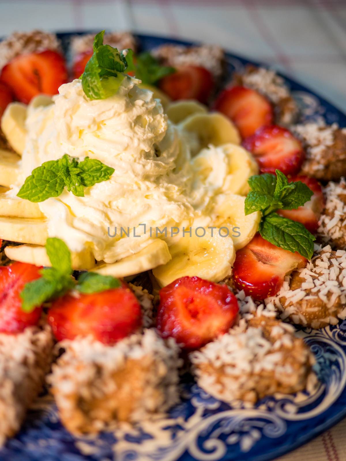 Chocolate dessert with banana, strawberry and mint under whipped cream