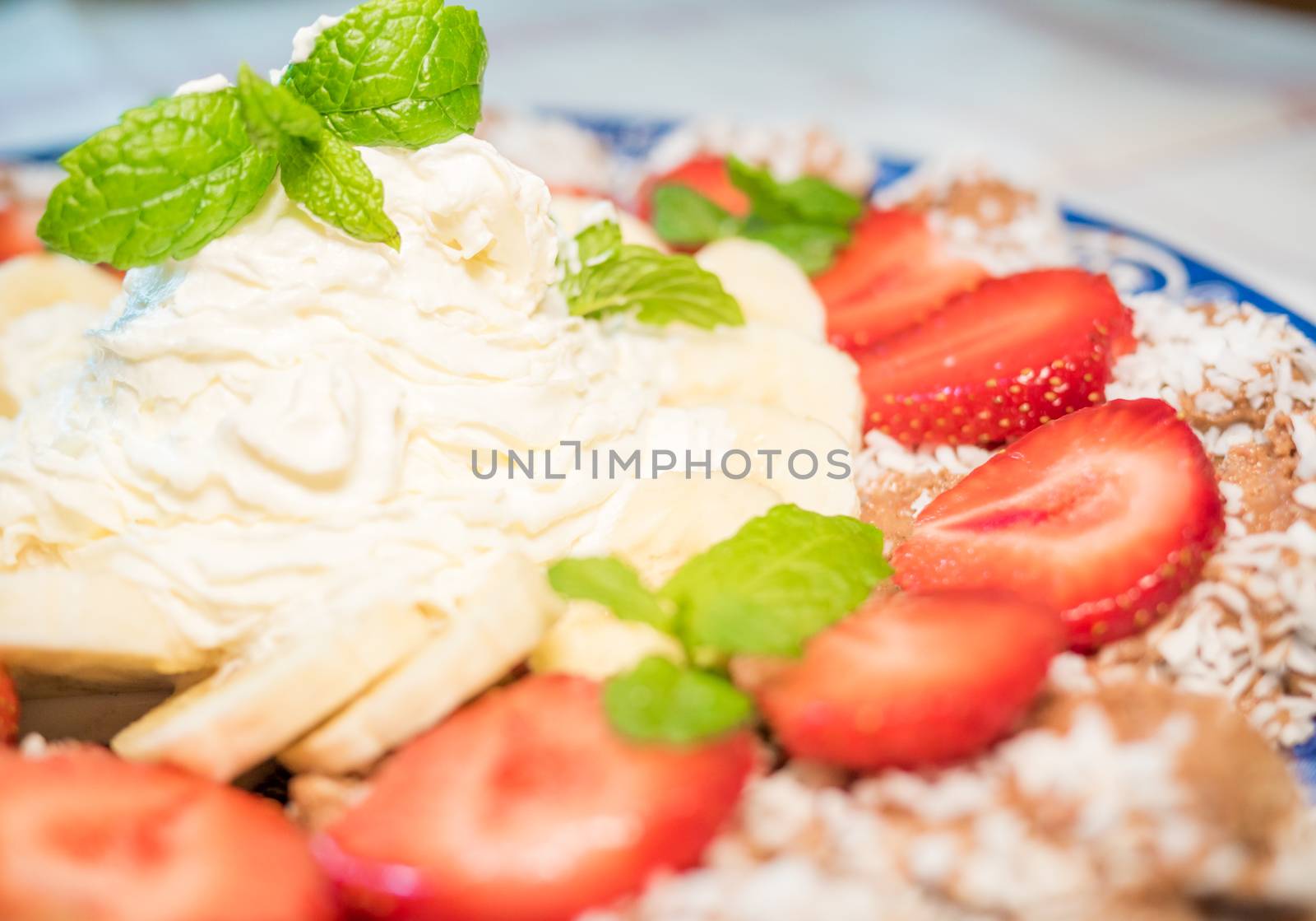 Chocolate dessert with banana, strawberry and mint under whipped cream