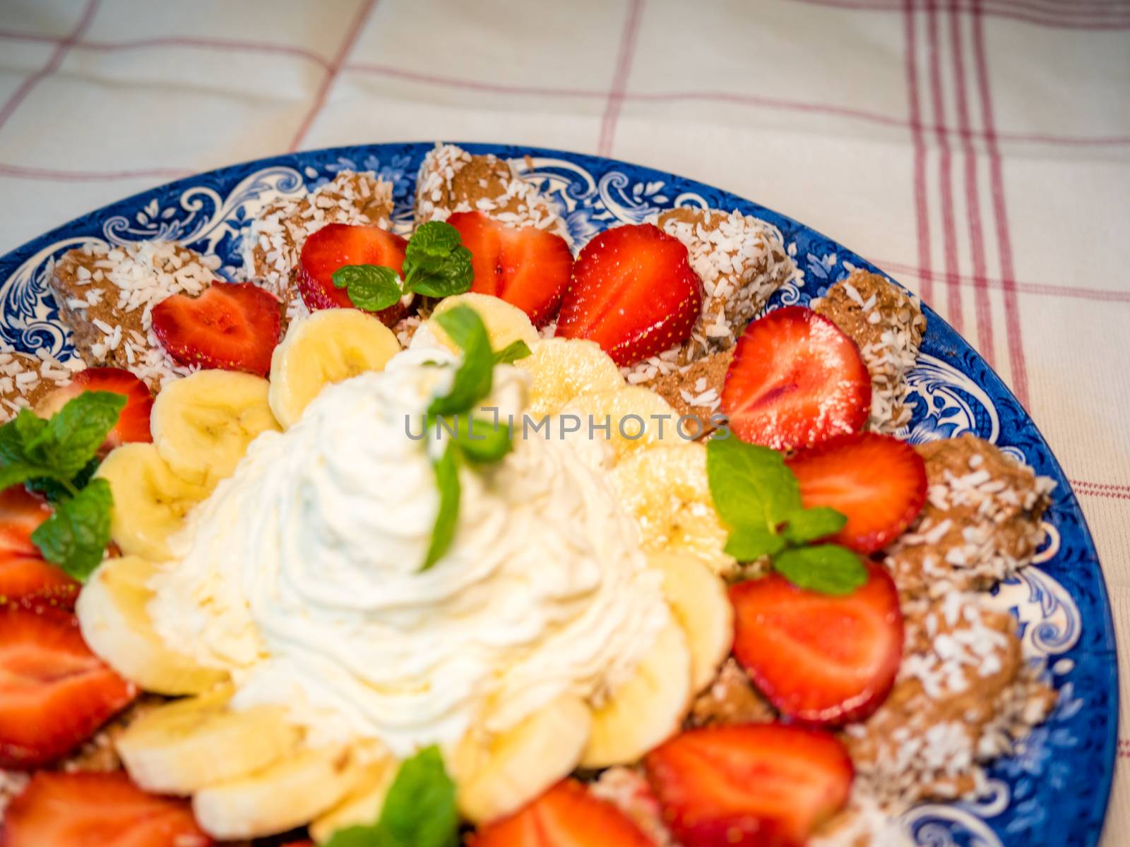 Chocolate dessert with banana, strawberry and mint under whipped cream