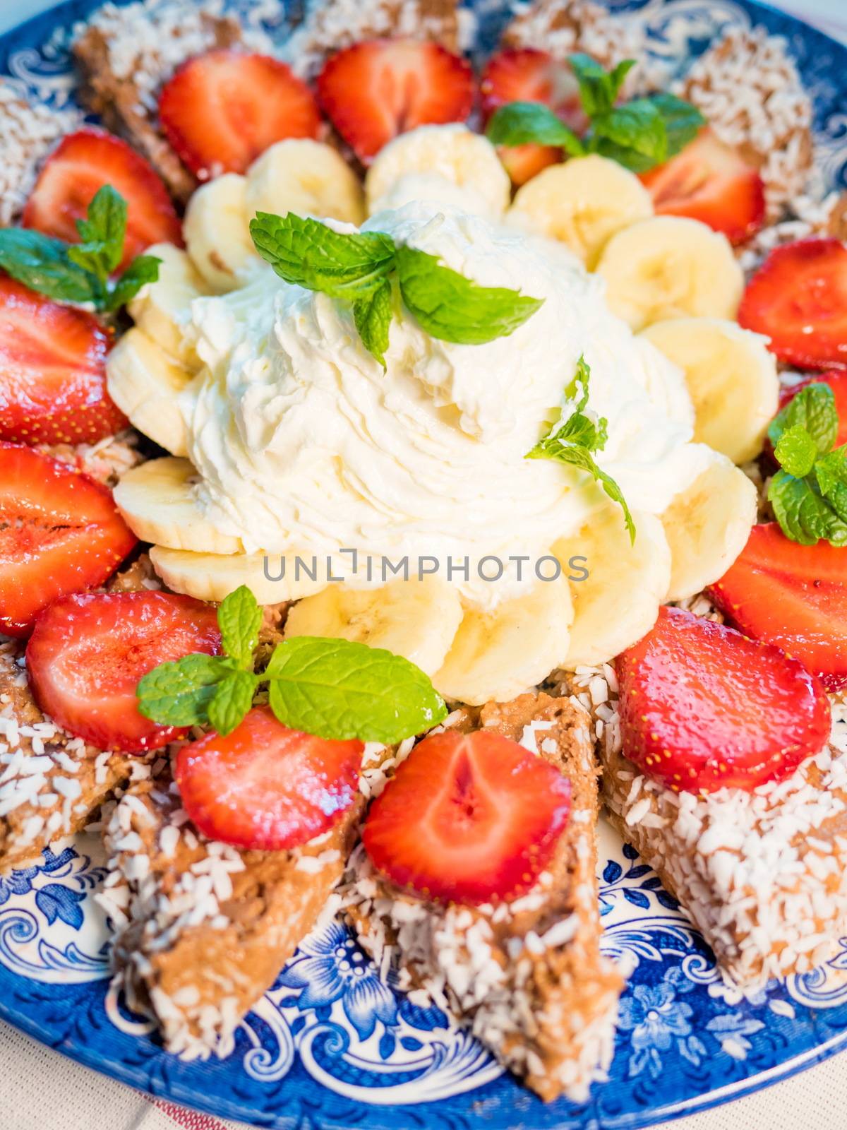 Chocolate dessert with banana, strawberry and mint under whipped cream