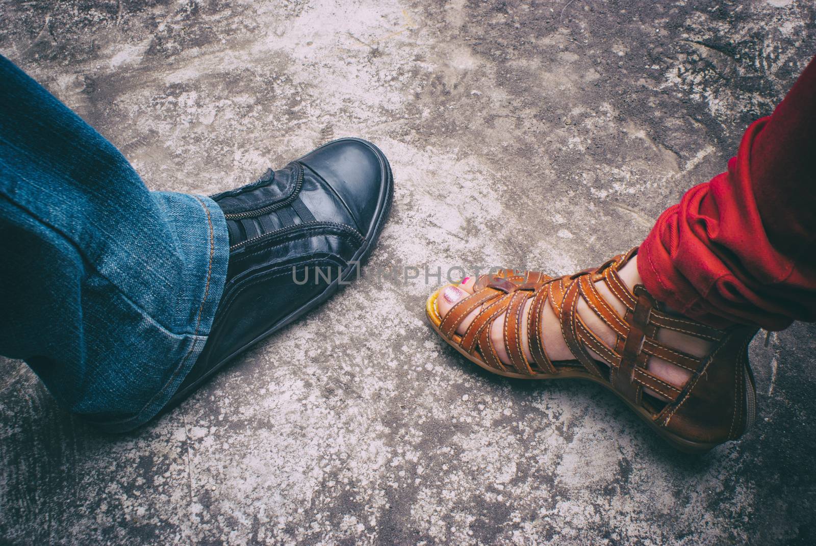 Photograph of a mans foot wearing a tennis shoe and a womans foot wearing a sandal