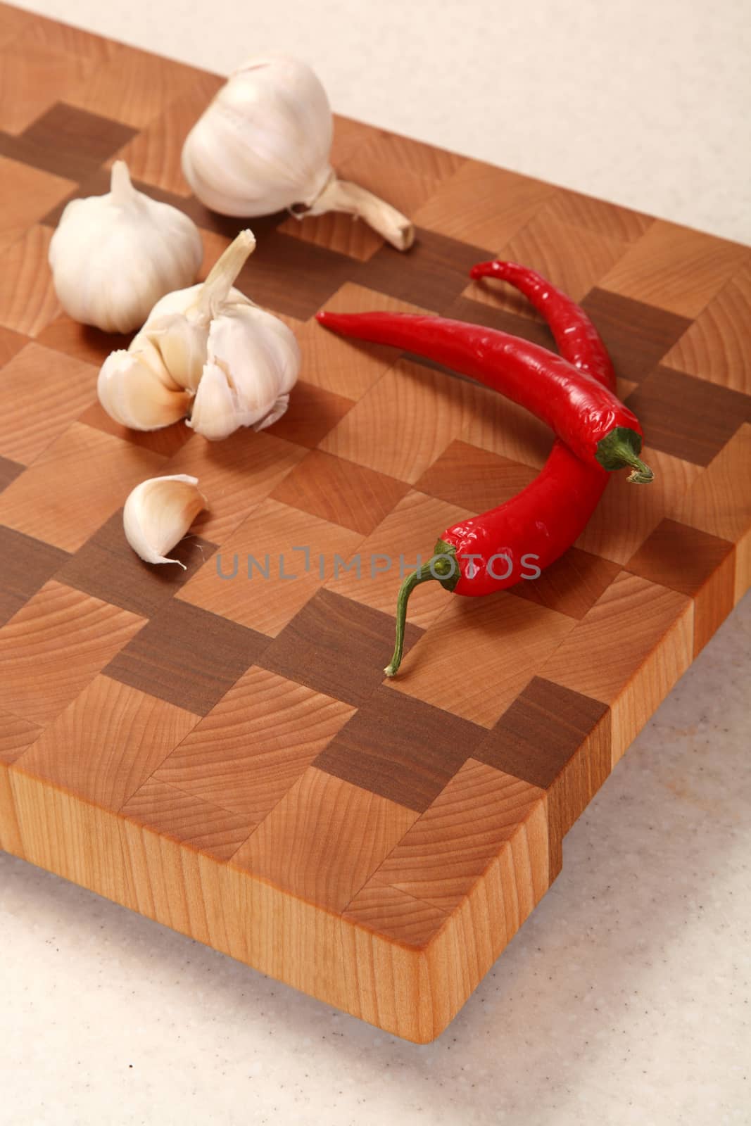 segment of garlic and two chili peppers on a chopping board