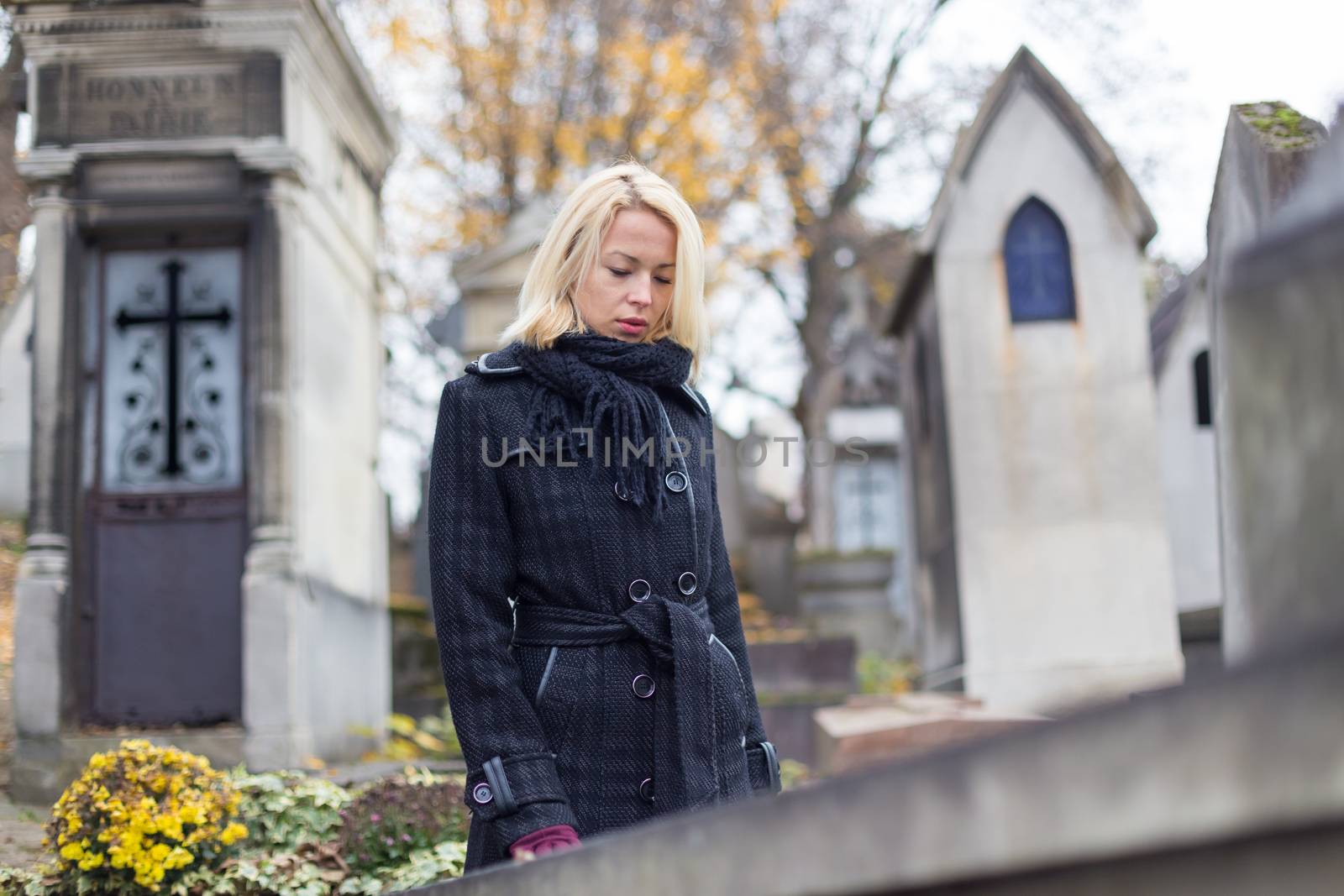 Solitary woman visiting relatives grave. by kasto