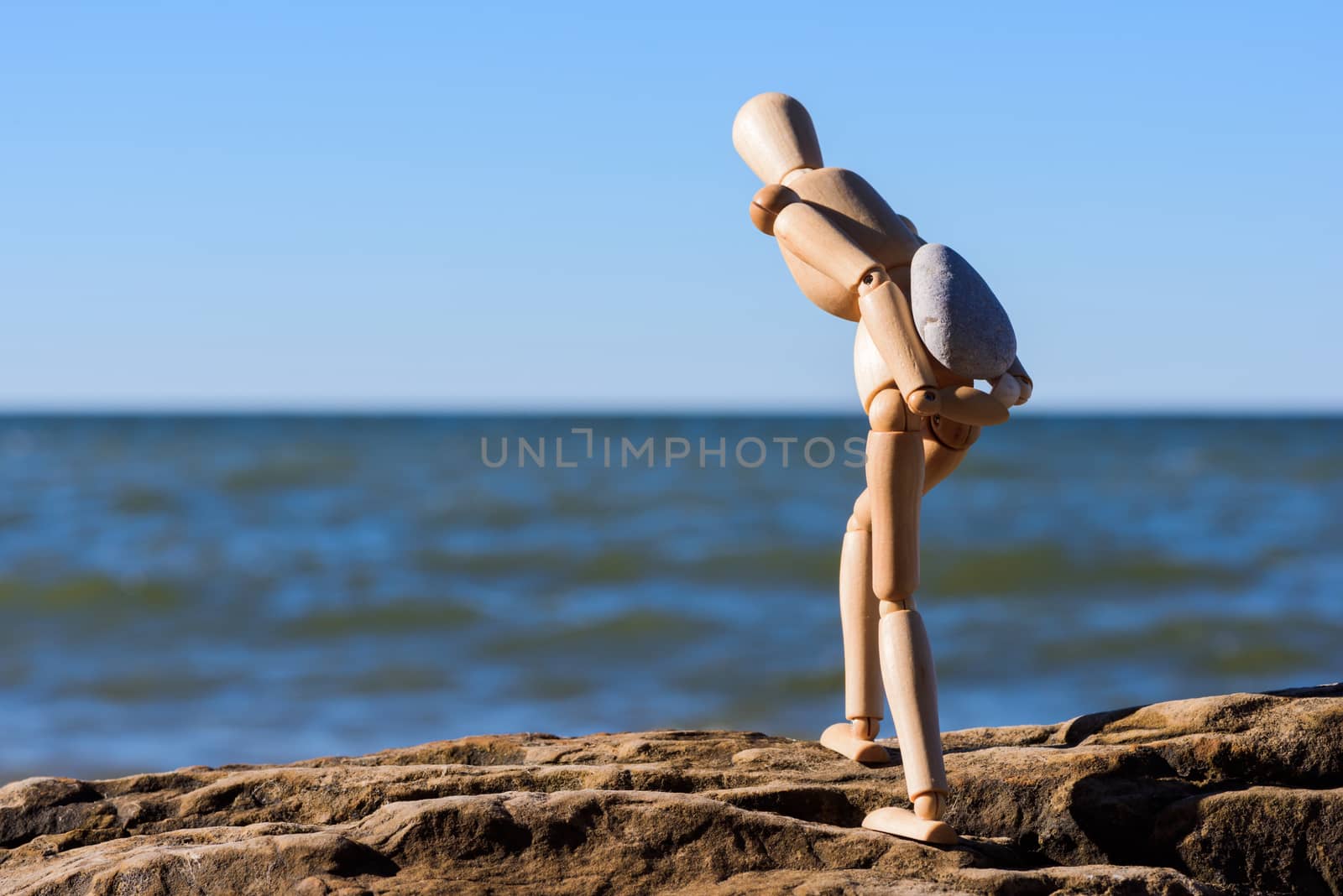 Mannequin carries a heavy stone on the coast