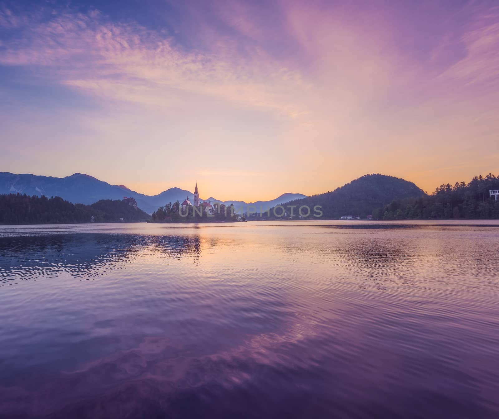 Little Island with Catholic Church in Bled Lake, Slovenia at Sunrise with Castle and Mountains in Background