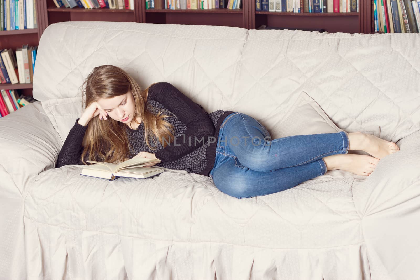 Happy Girl Resting on Sofa at the Living Room While Reading her Favorite Novel Book