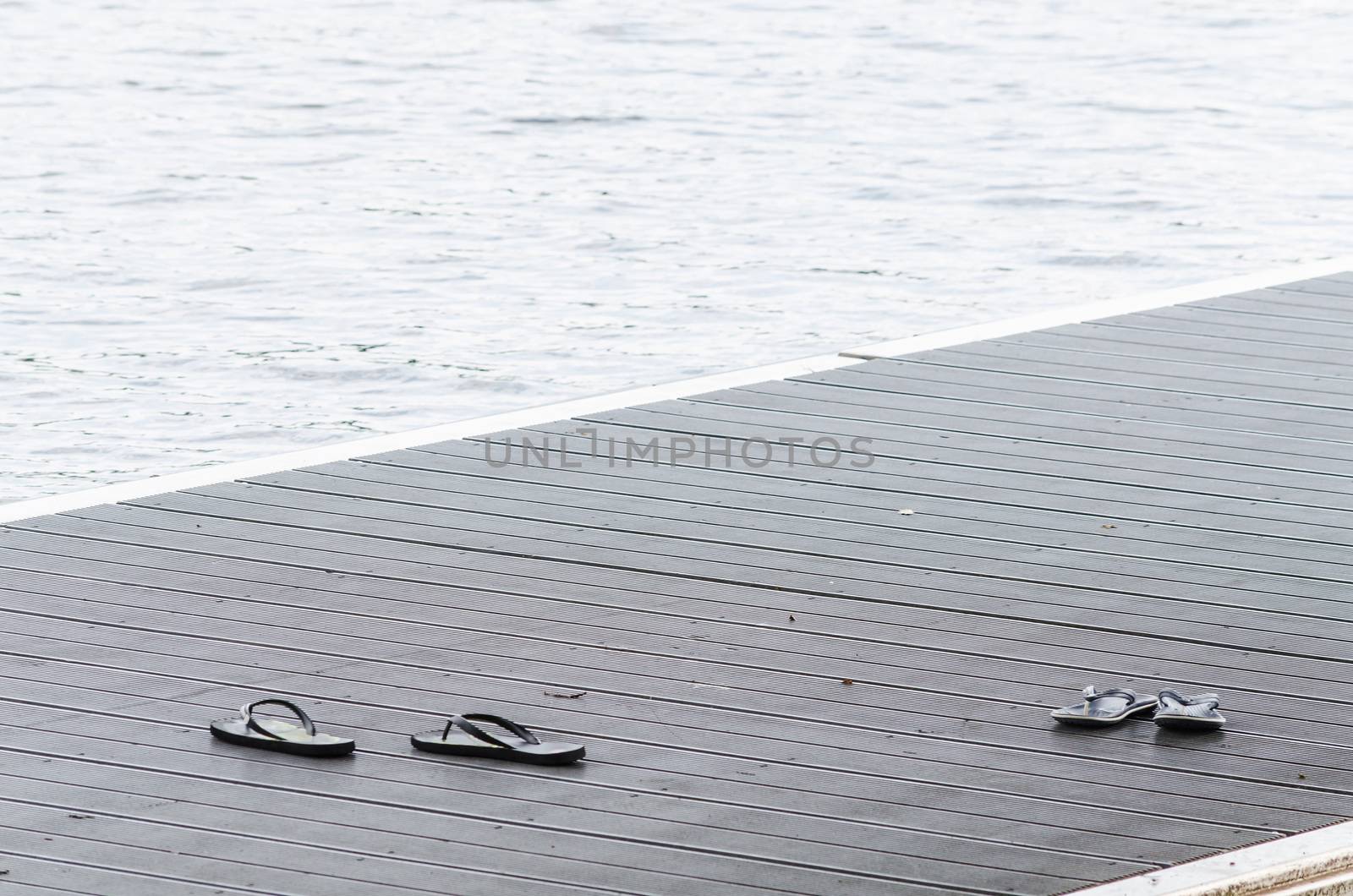 Black sandals on a boat dock on a promenade along the lake.