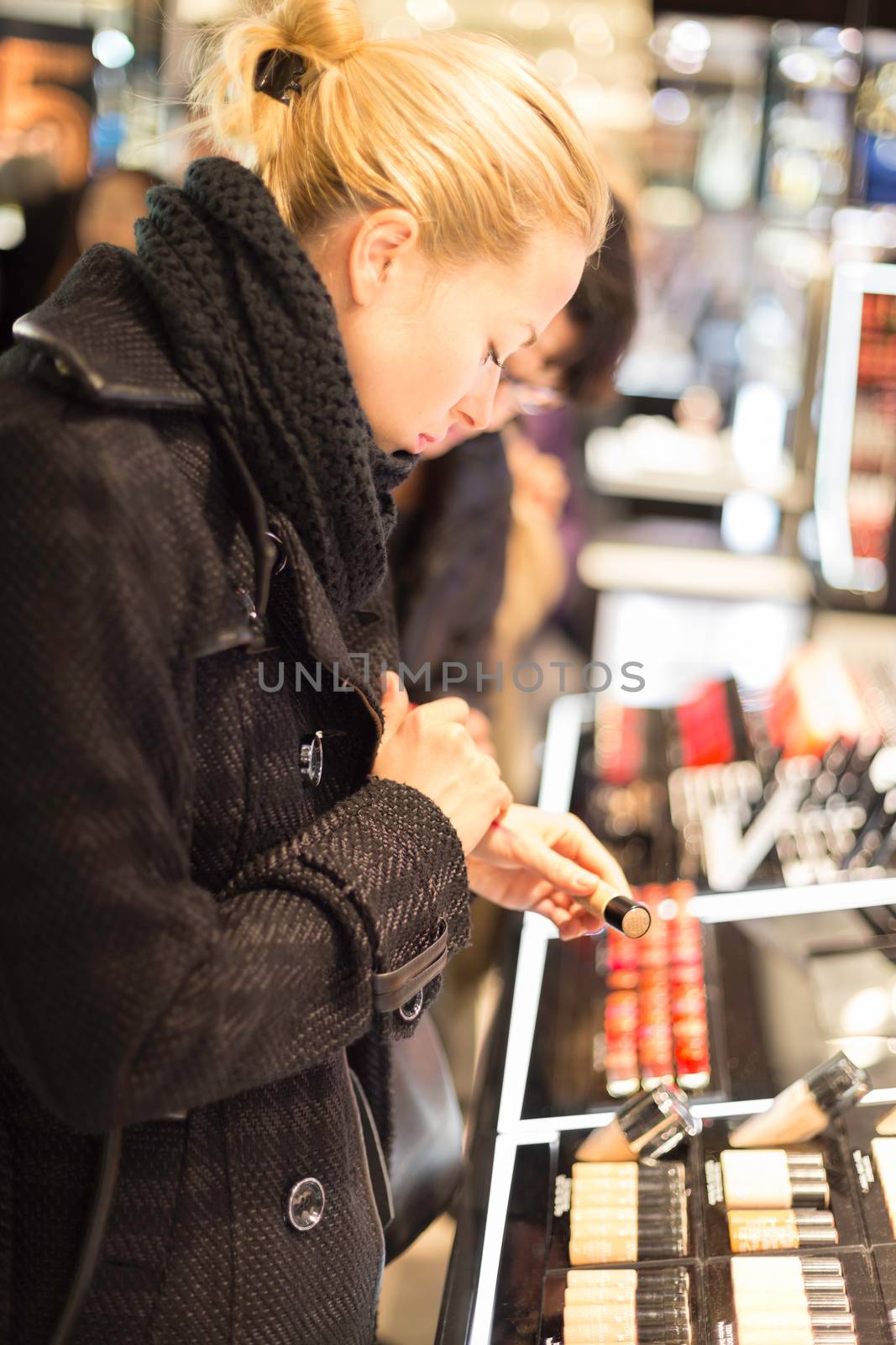 Beautiful blond lady testing  and buying cosmetics in a beauty store.