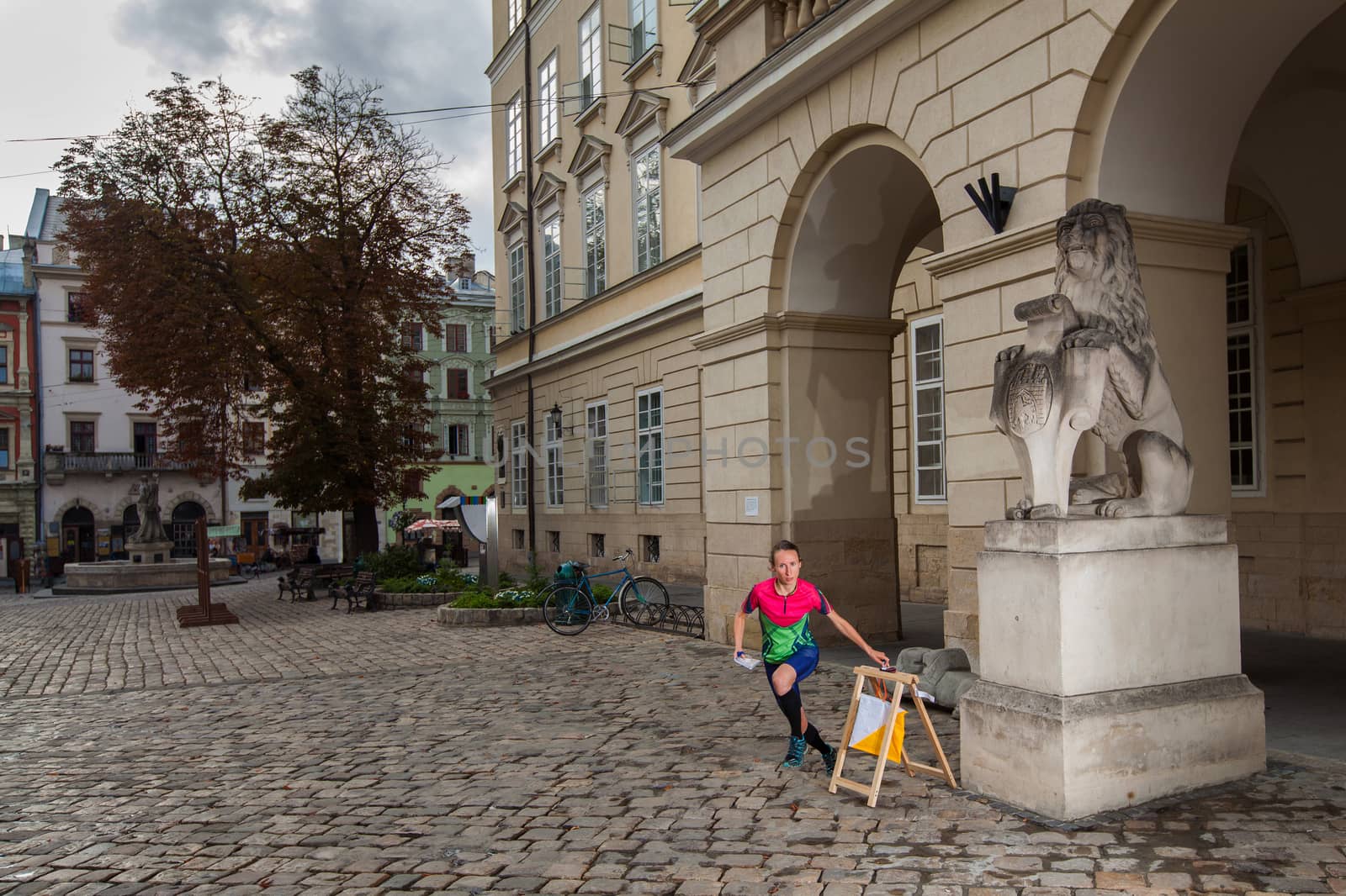 Woman punching at control point, taking part in orienteering city race competitions in old european city