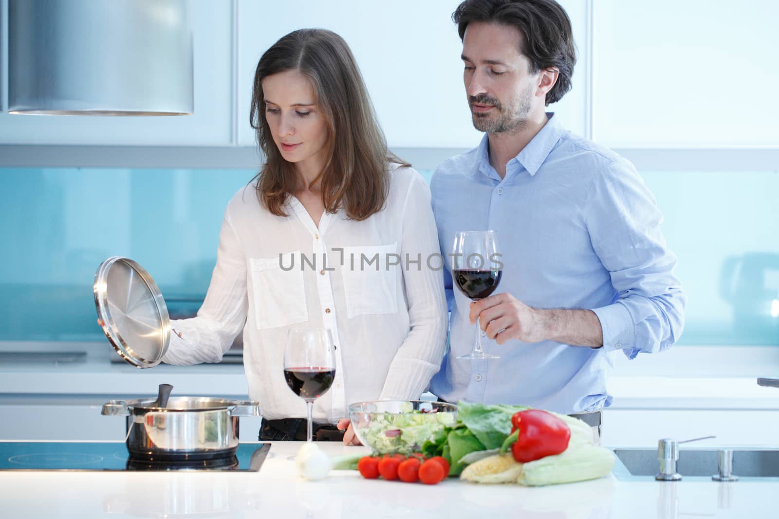 Portrait of a couple having a glass of red wine while cooking dinner