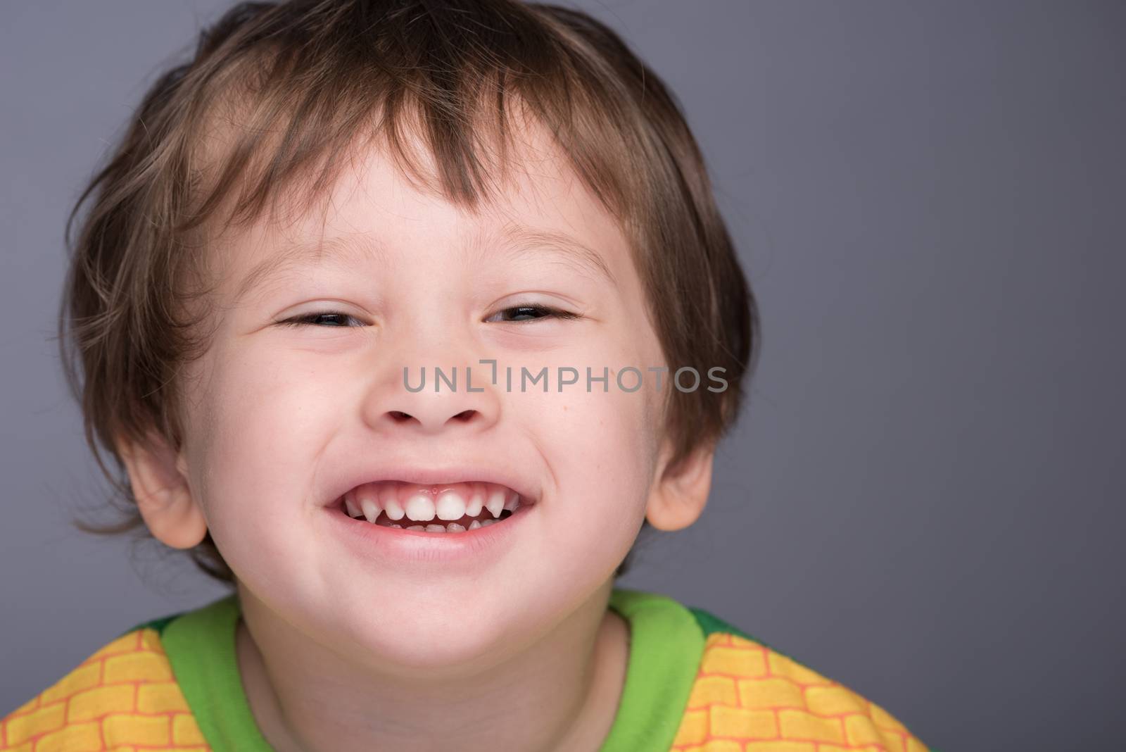 A happy 3 year old Japanese/Caucasian boy smiling.
