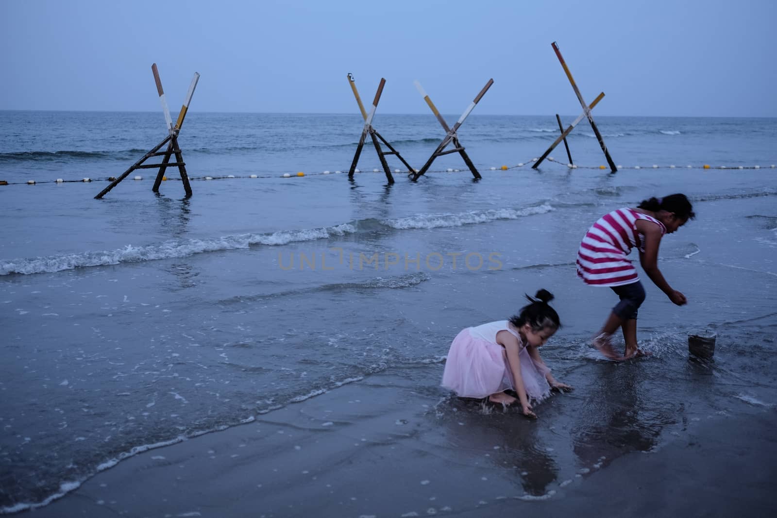 MALAYSIA, Kuala Terengganu:  Two young girls play on the beach in Kuala Terengganu, Malaysia on September 21, 2015. Haze covered Malaysia for several days, but cleared on Monday morning. The country suffers from poor air quality and the haze often blankets the region. Malaysia and neighboring countries are trying to figure out a way to combat the haze which causes problems in the area.