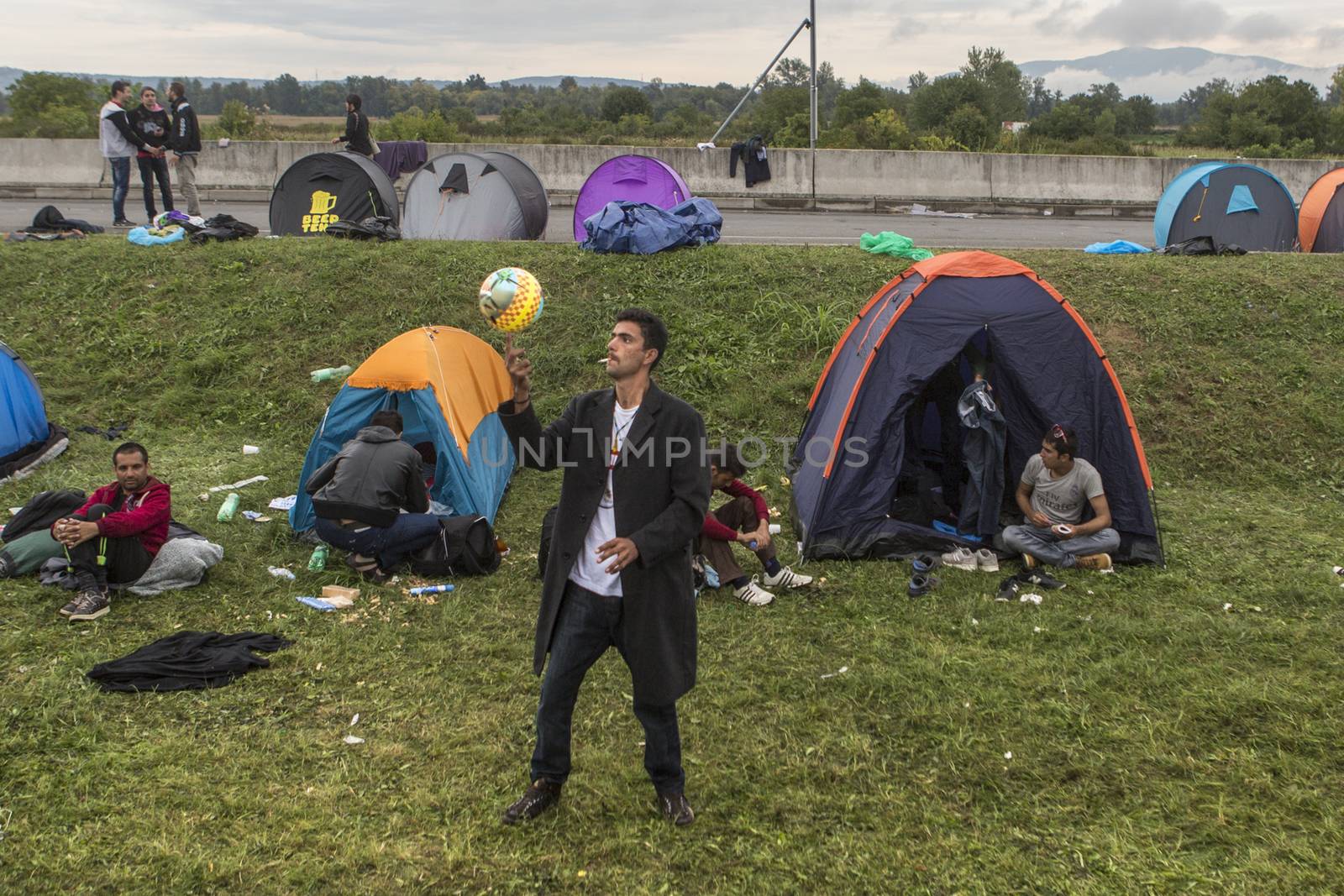 CROATIA, Harmica: One man smokes and plays soccer as refugees on the border between Croatia and Slovenia find ways to pass the time on September 20, 2015.  Refugees are at the mercy of European authorities as they attempt to escape their war-ravaged countries.