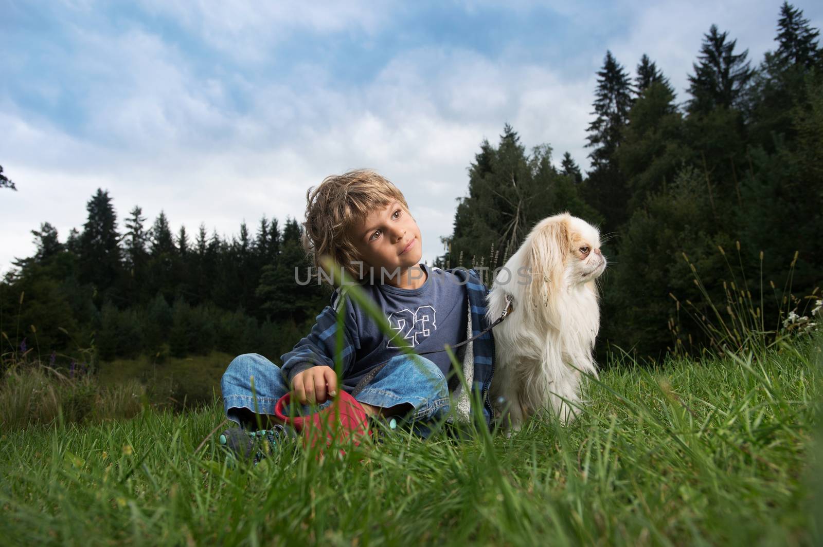 Cute little boy cuddling his dog in nature.